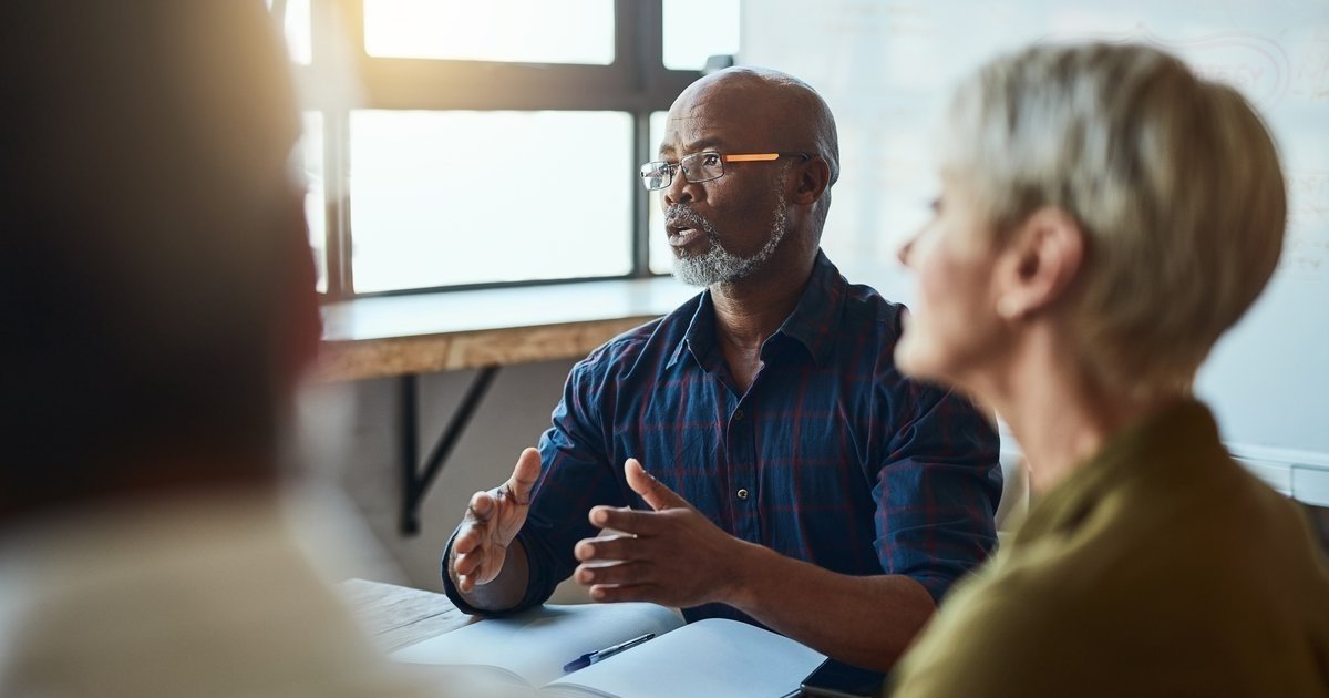 Veteran business owner reviewing succession plan documents with a key employee in a professional office setting.