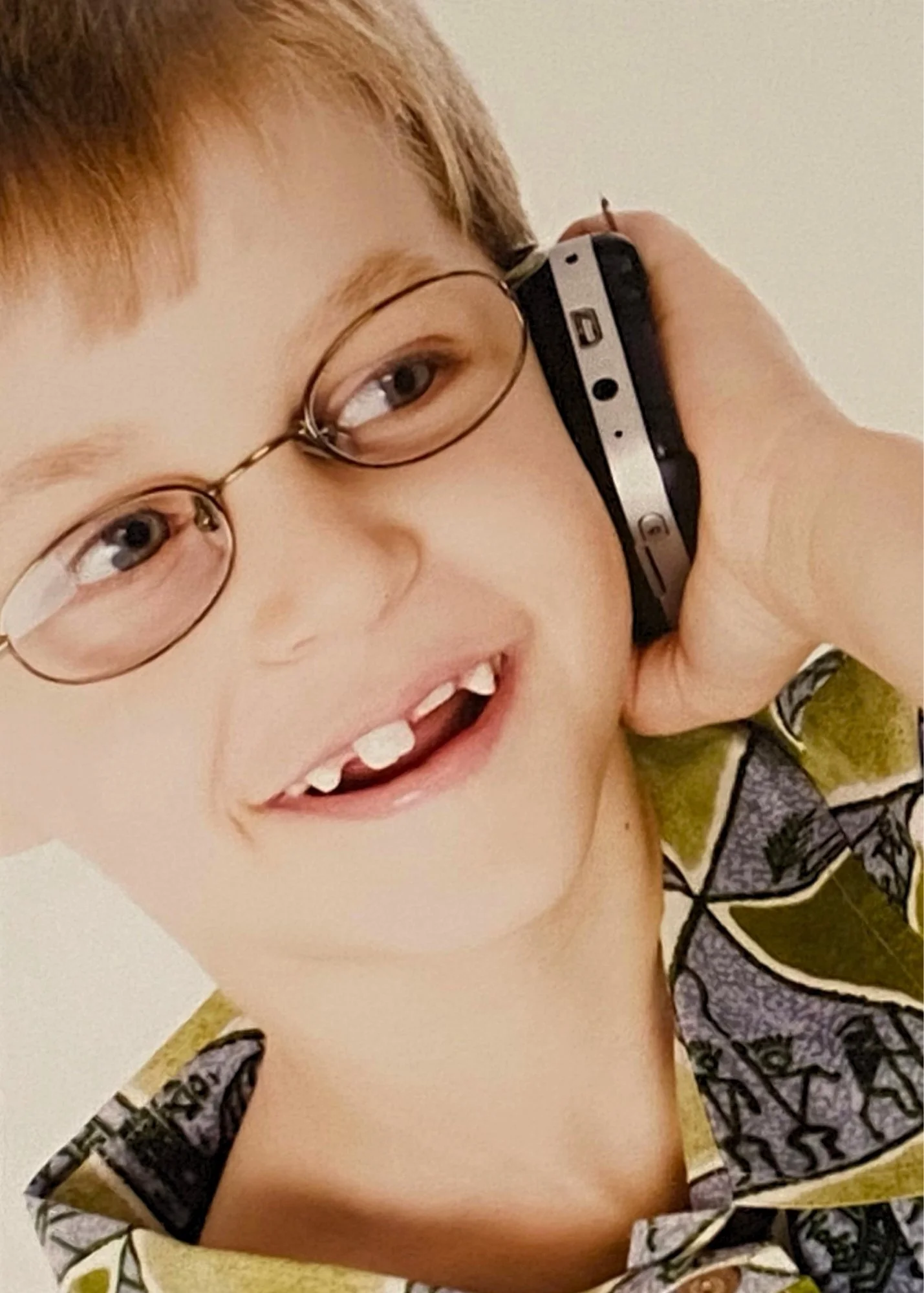 Young boy with glasses holding cell phone to his ear, smiling and talking during speech therapy for children in Norwalk, CT.
