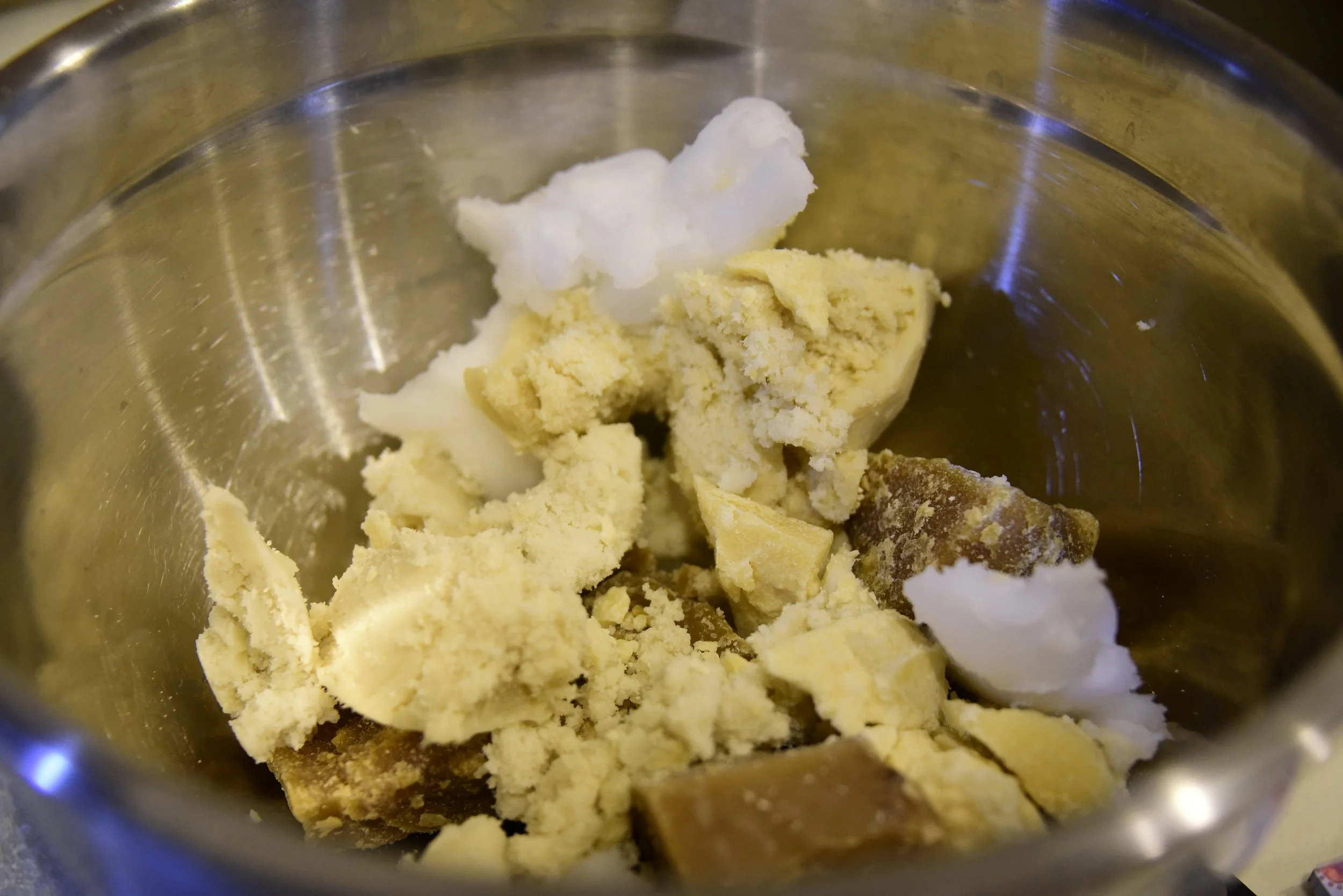 Shea butter, coconut oil, beeswax, and cacao butter in a mixing bowl.