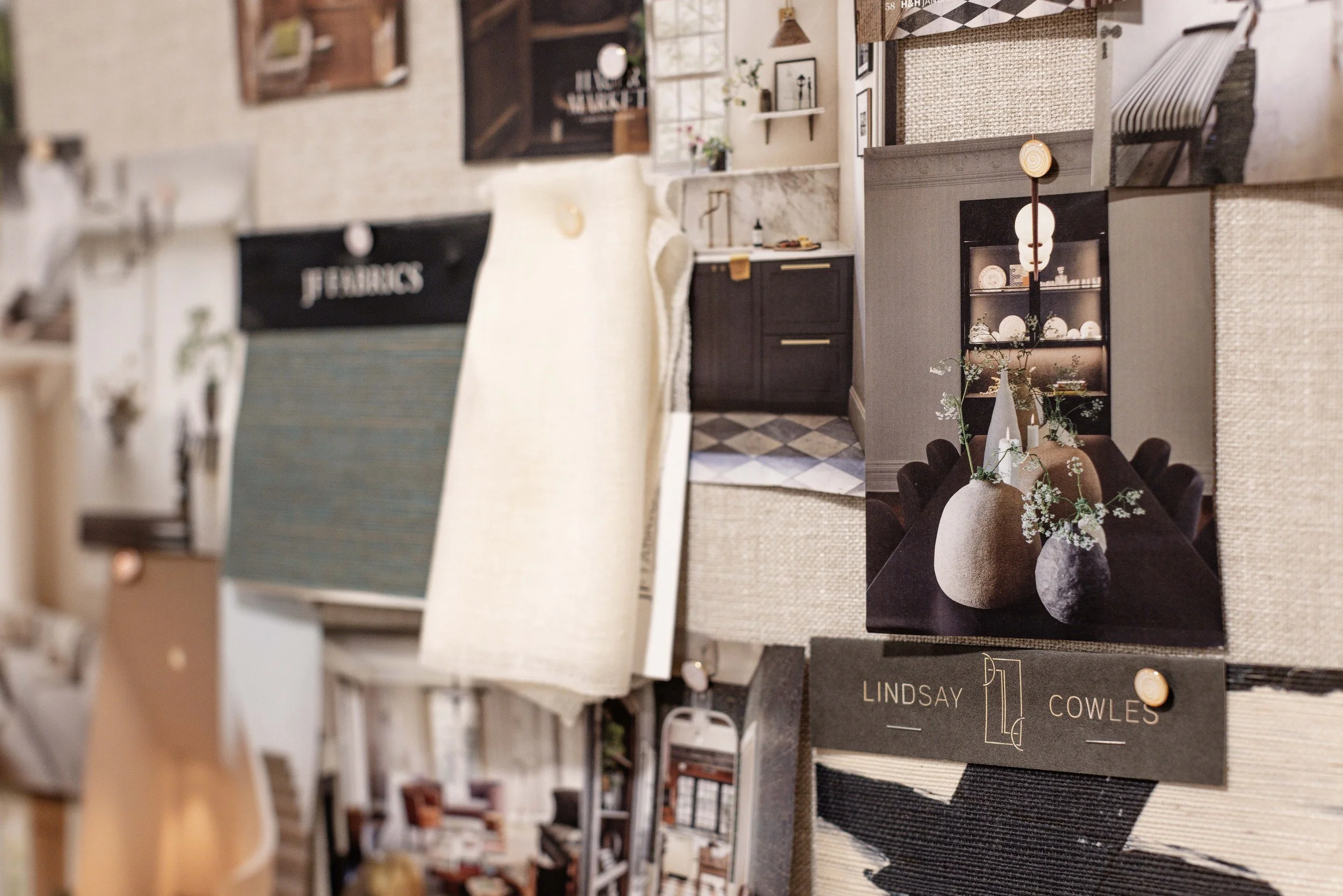 A collage of interior design photos including a kitchen with dark cabinets, a dining table with vases and flowers, and tableware on shelves. A sample fabric swatch and a numbered fabric sample card labeled 'Lindsay Cowles' are pinned to a board.