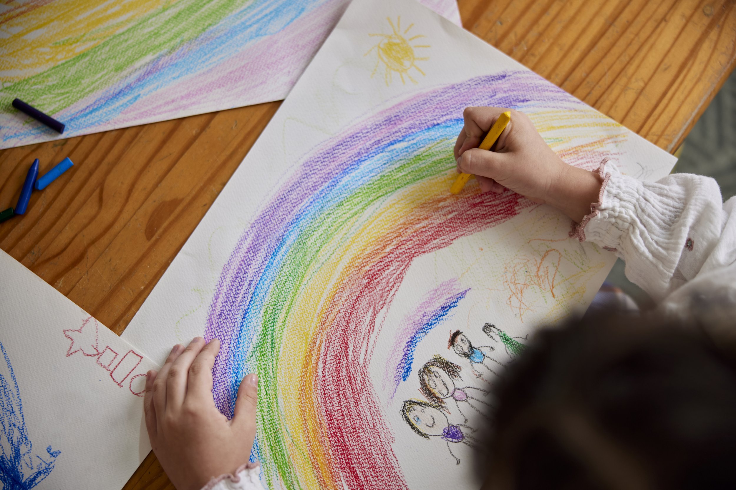 A kid drawing of a rainbow and family