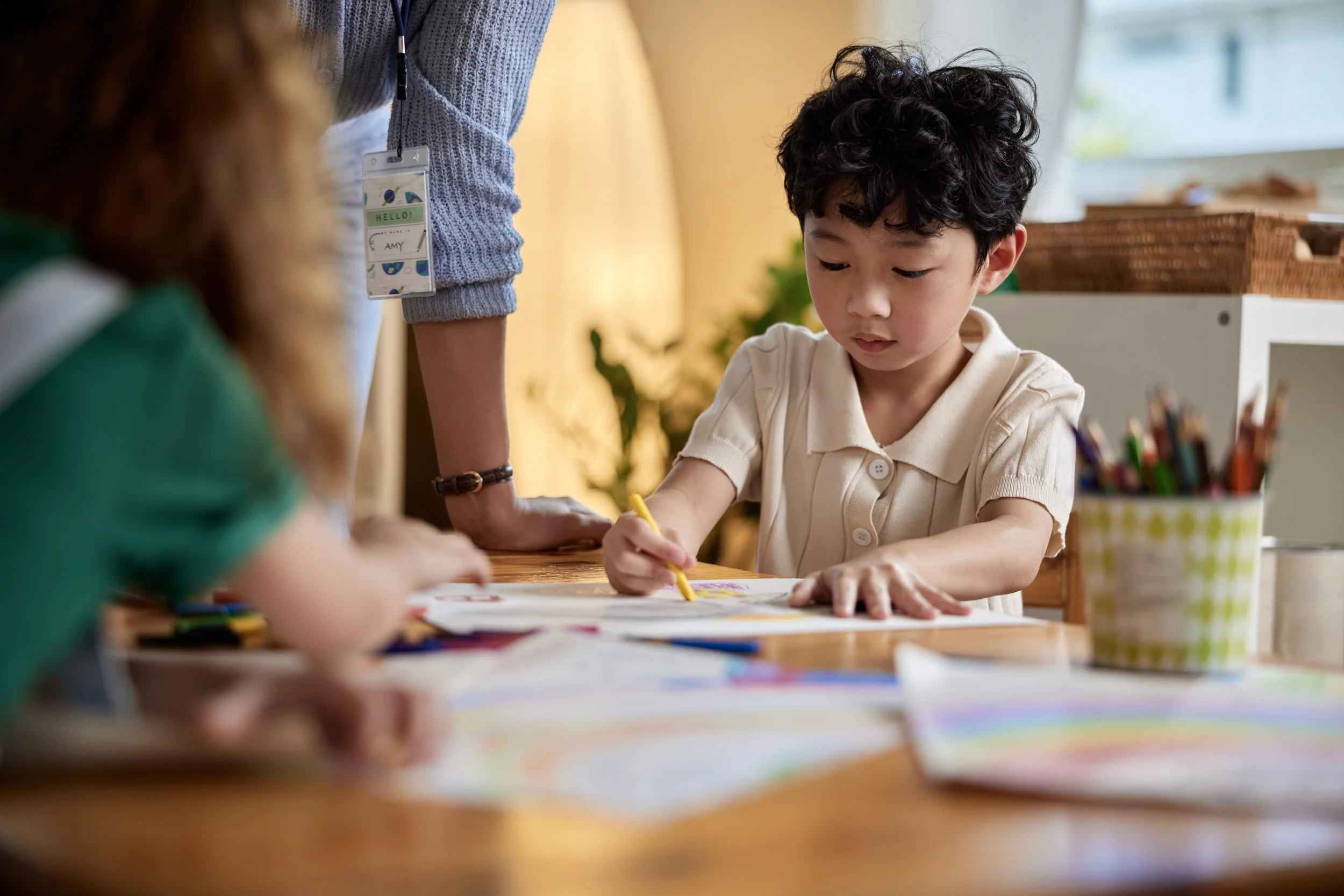 Young kid drawing at daycare with his teacher