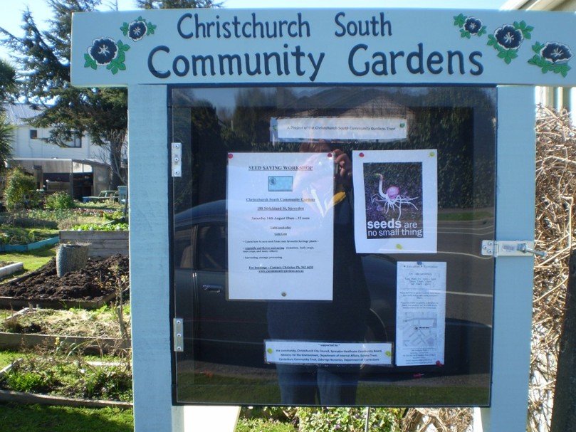 Information board at Christchurch South Community Gardens with notices about seed saving workshop and garden updates.