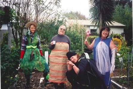 Four people dressed in costumes standing outdoors in a garden.