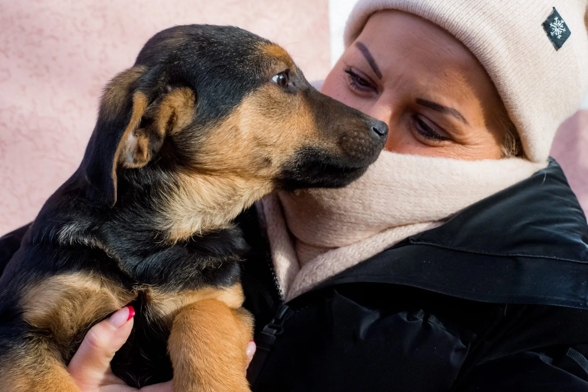 A woman holding a puppy close to her face, both looking at each other affectionately.