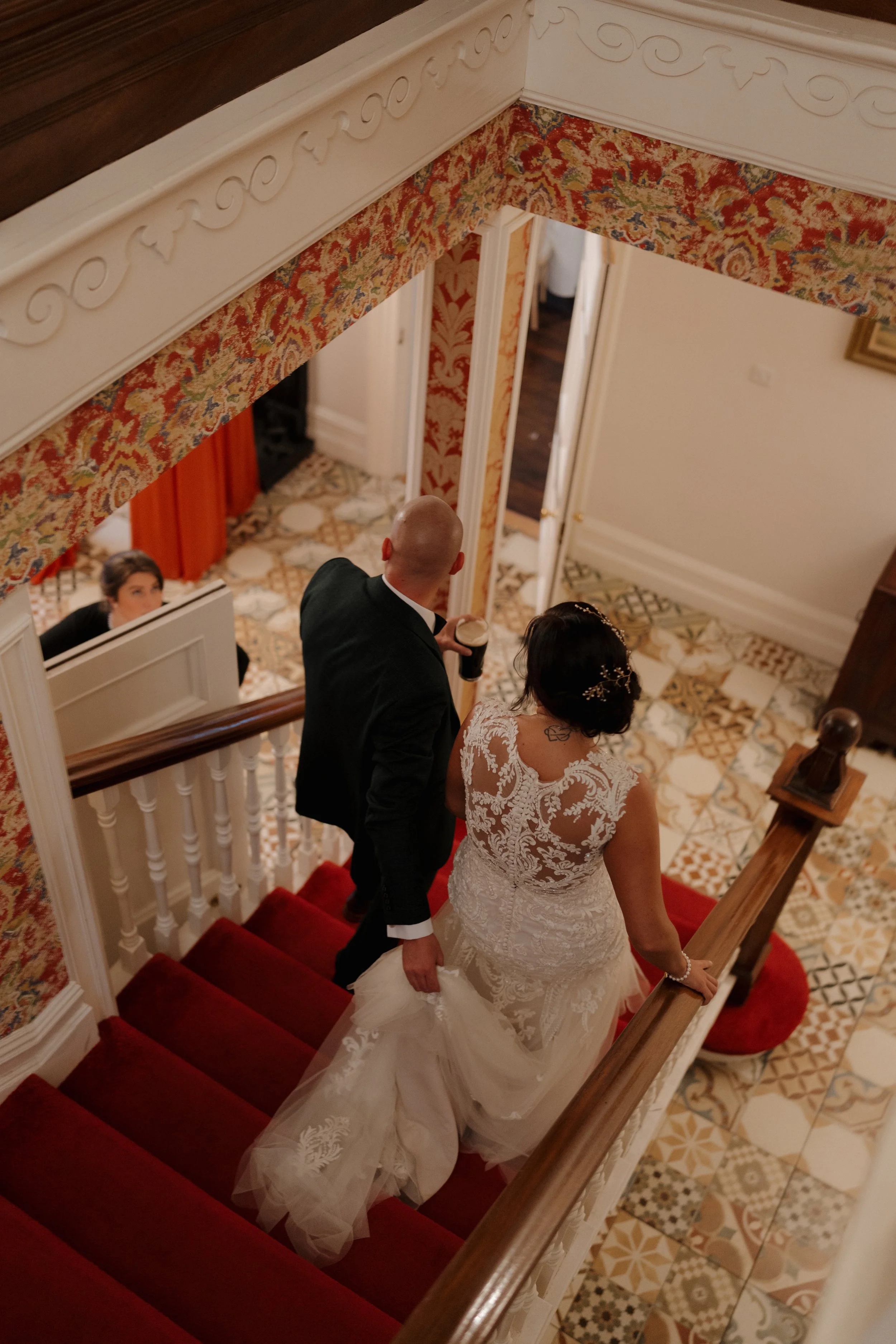 A bride and groom walking down a staircase, viewed from above, during their wedding ceremony.
