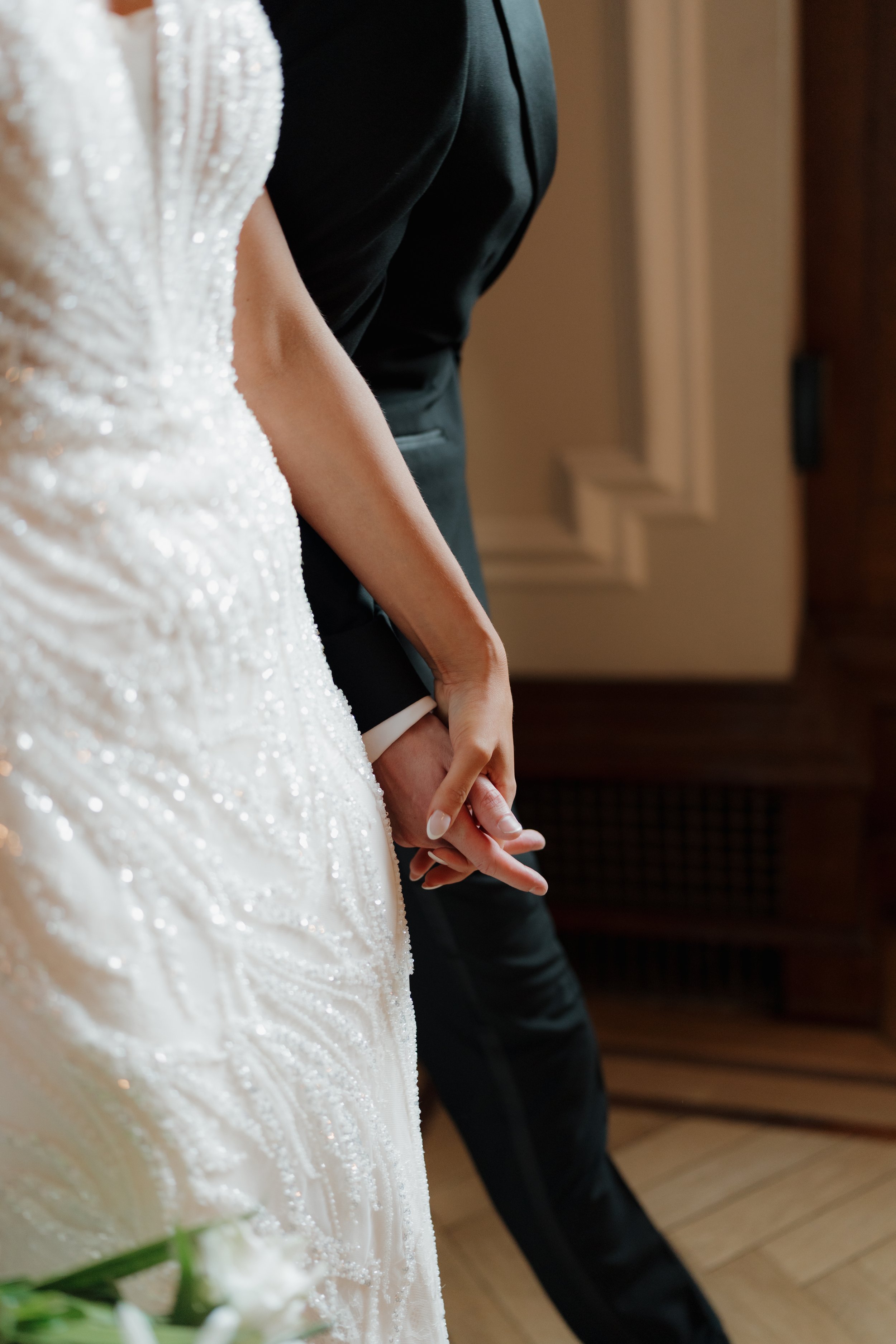 Close-up of a bride and groom holding hands during a wedding ceremony.