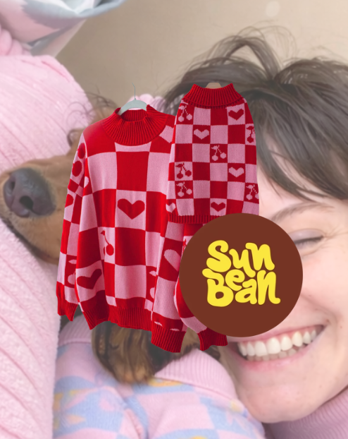 A woman smiling with eyes closed, holding a dog with a pink blanket, and a large sticker showing two red and pink checkered sweaters with hearts and flower patterns and the Sun Bum logo.