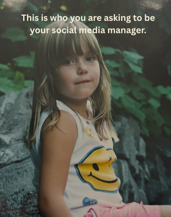 A young girl sitting outdoors with rocks and green foliage in the background. She has shoulder-length blonde hair and is wearing a white sleeveless shirt with a yellow smiley face logo and pink pants. The text overlay reads, 'This is who you are asking to be your social media manager.'