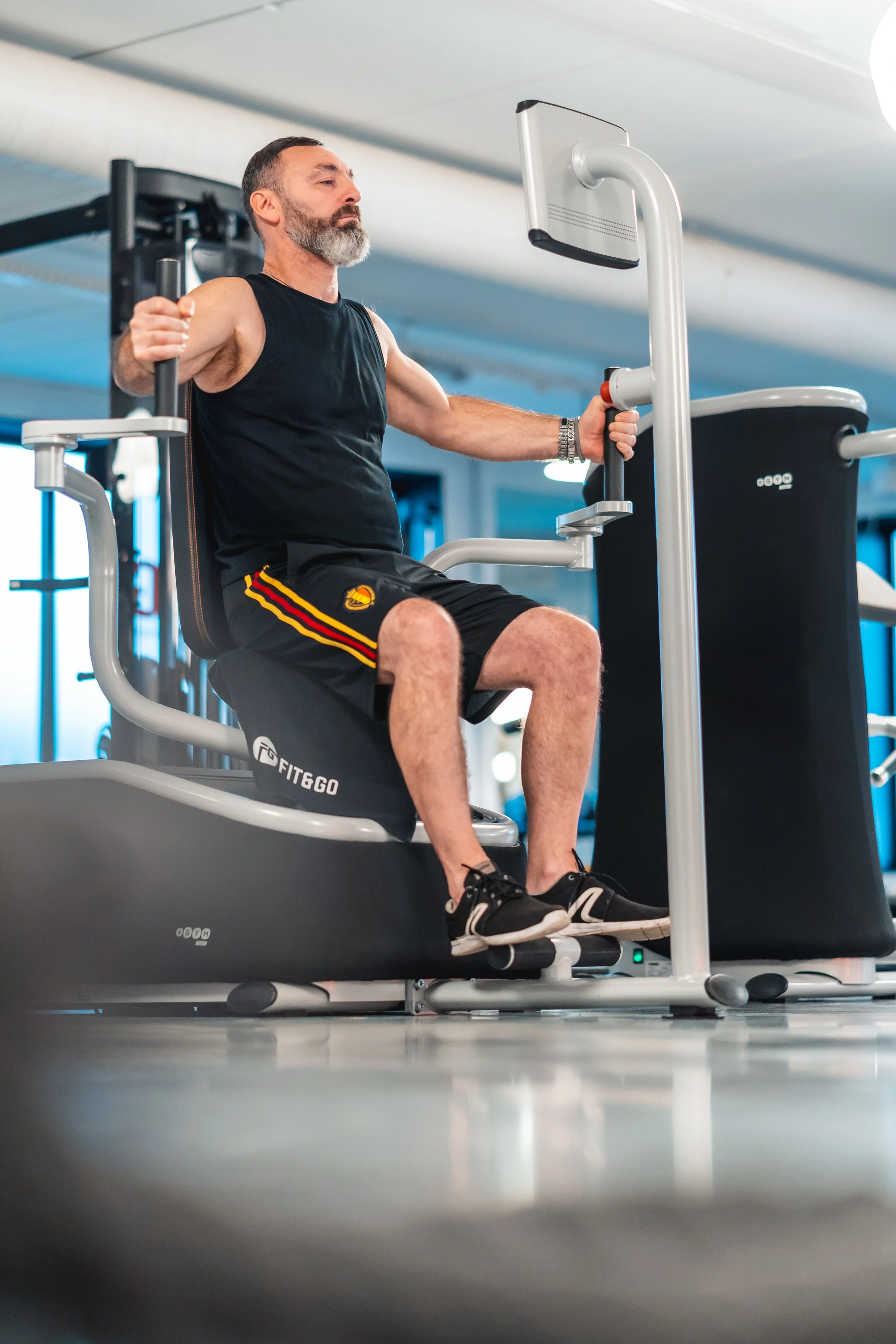 Een man die in een sportschool op een fitnessapparaat zit en traint.