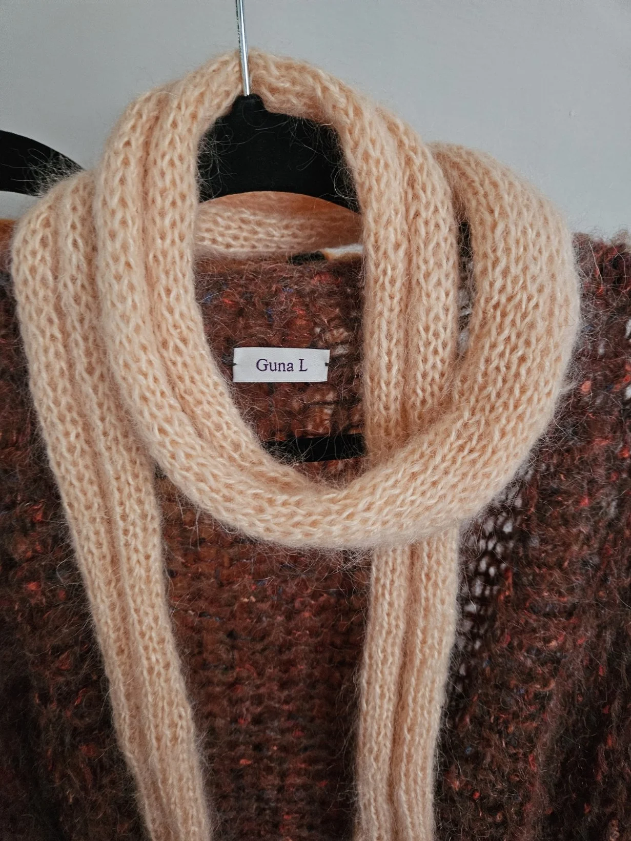 Handknitted scarf in peach colour over brown cardigan.
