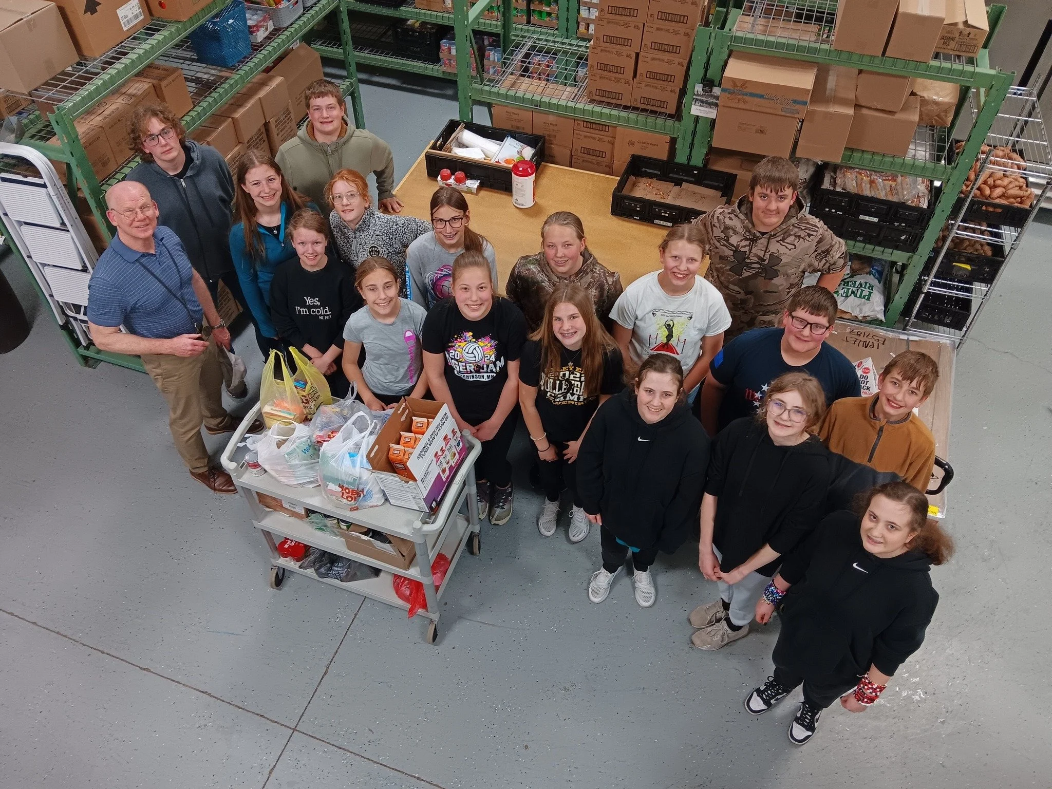 Group of food share volunteers looking up at camera surrounded by food