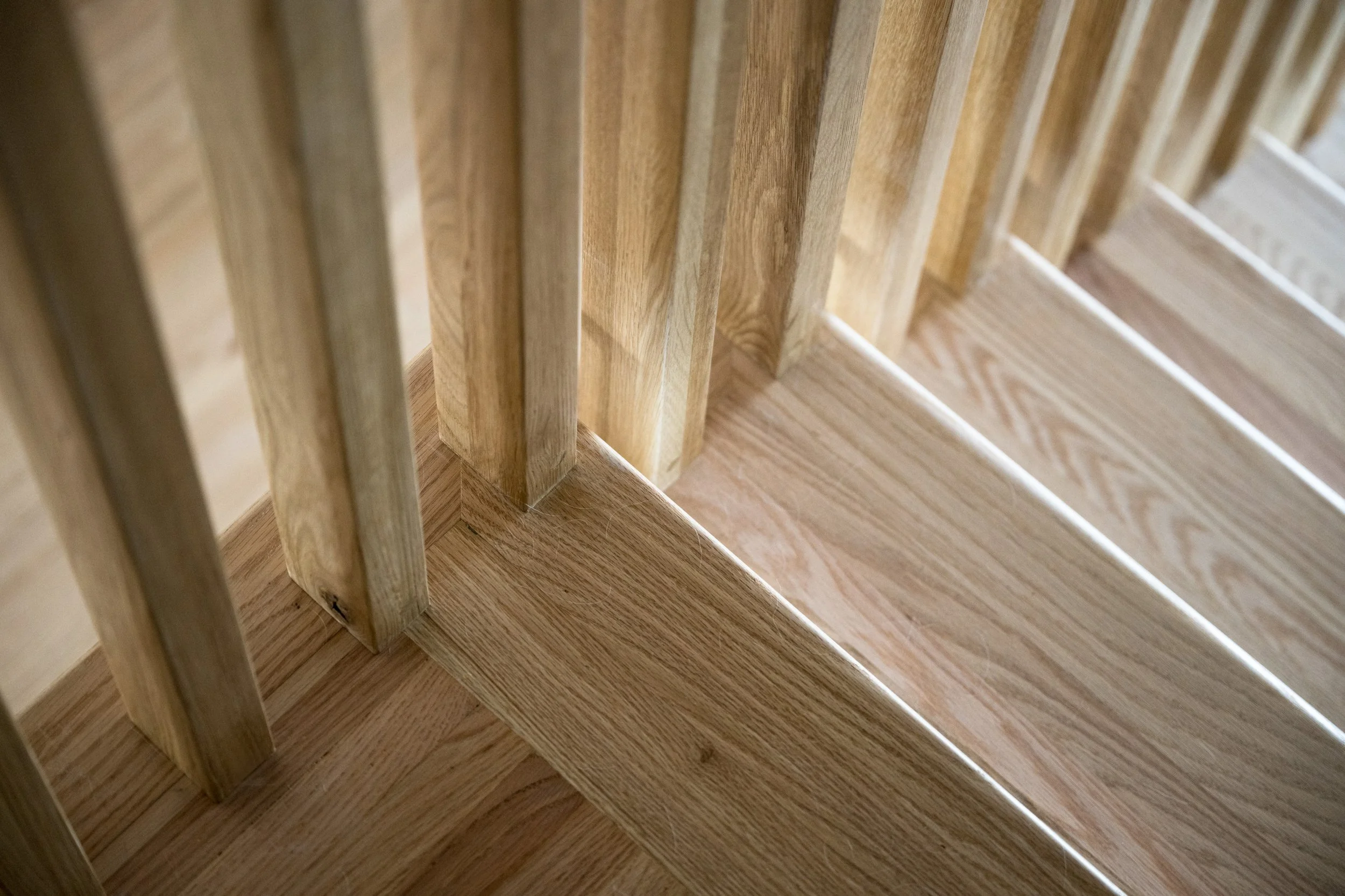 Close-up view of a wooden staircase with vertical balusters and horizontal treads, showing custom millwork and carpentry. 