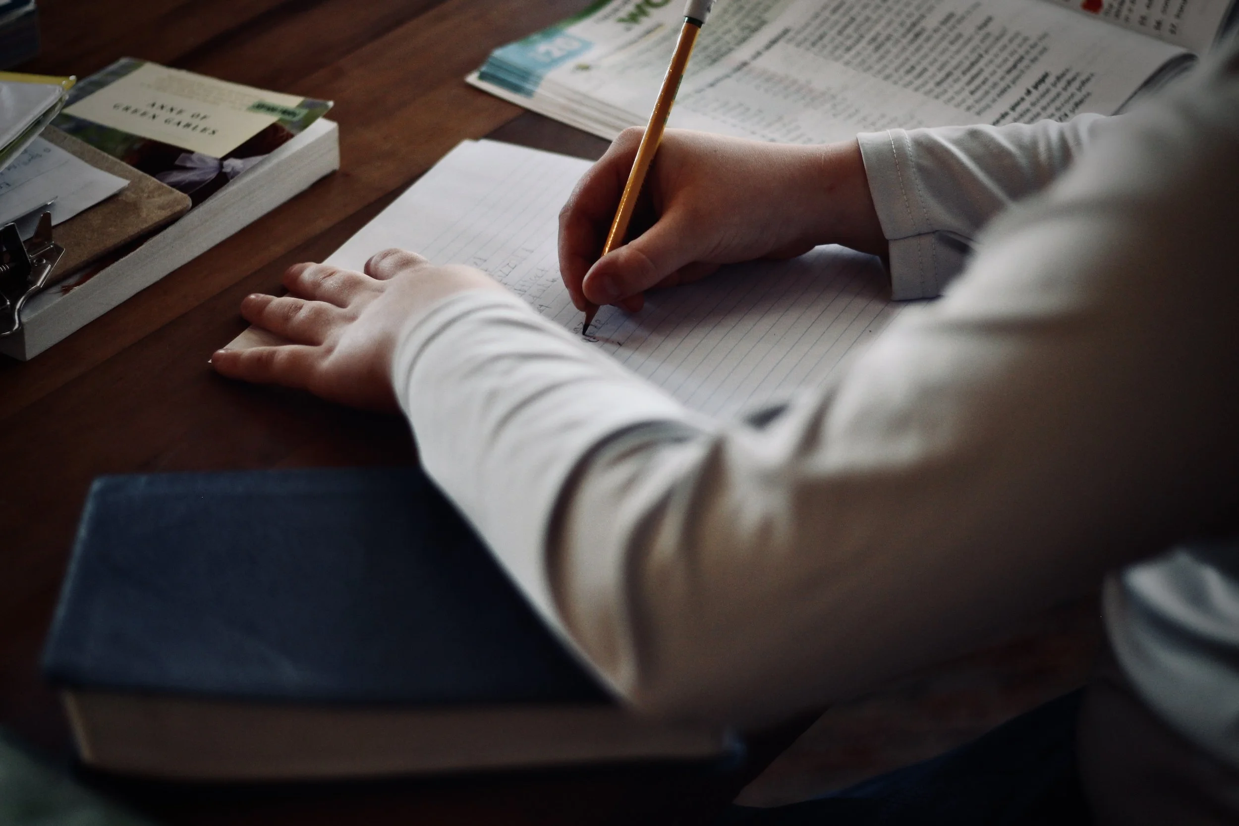 Hands writing a letter on a wooden desk
