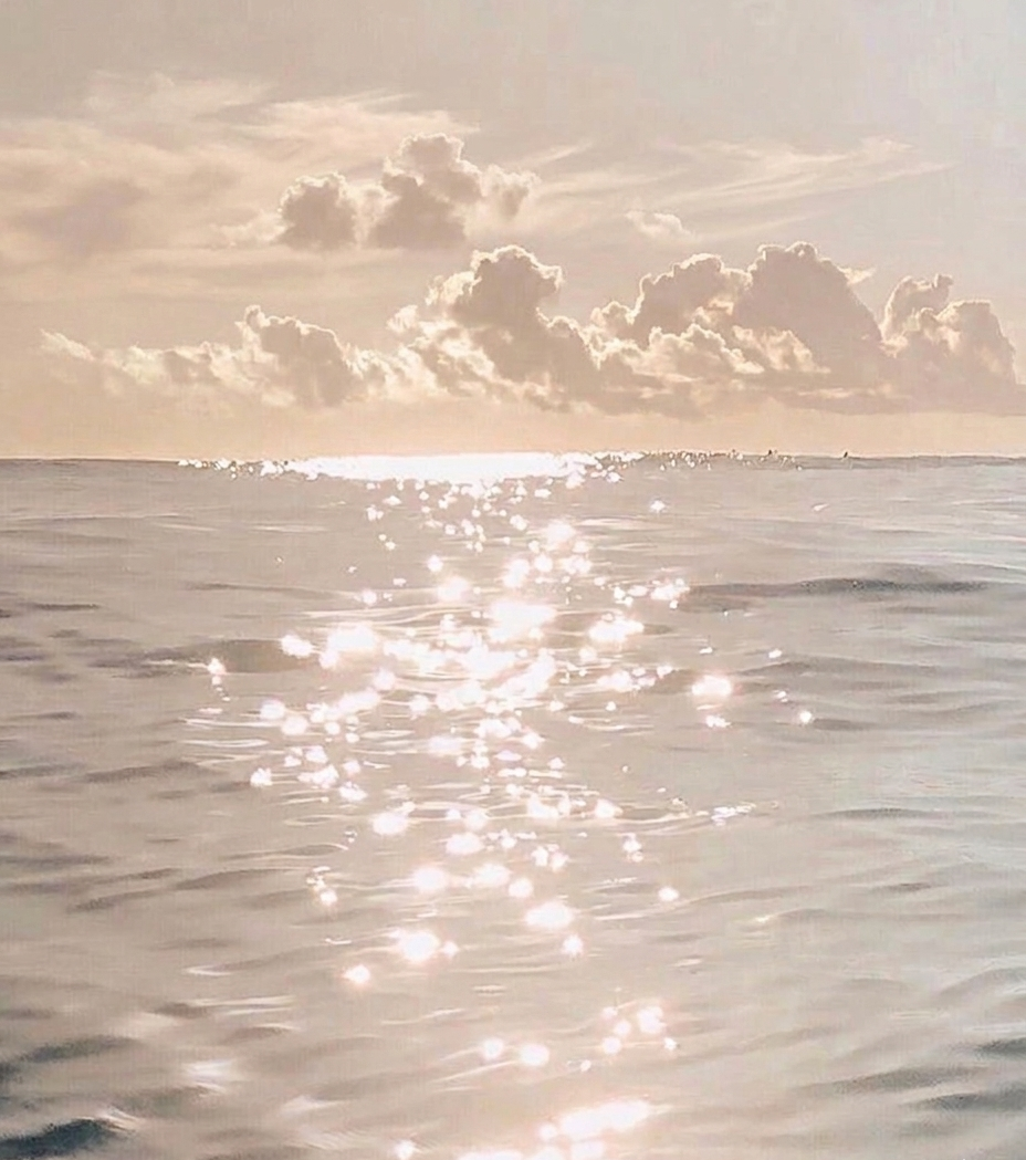 Sunlit ocean scene with clouds in the sky and sparkling sunlight on the water surface