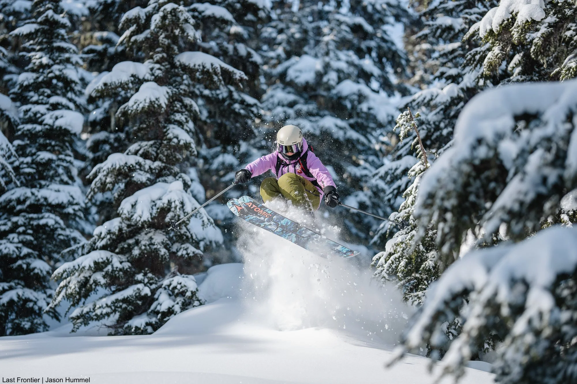 Skier launching off a natural snow pillow among the old growth trees at Ripley Creek.