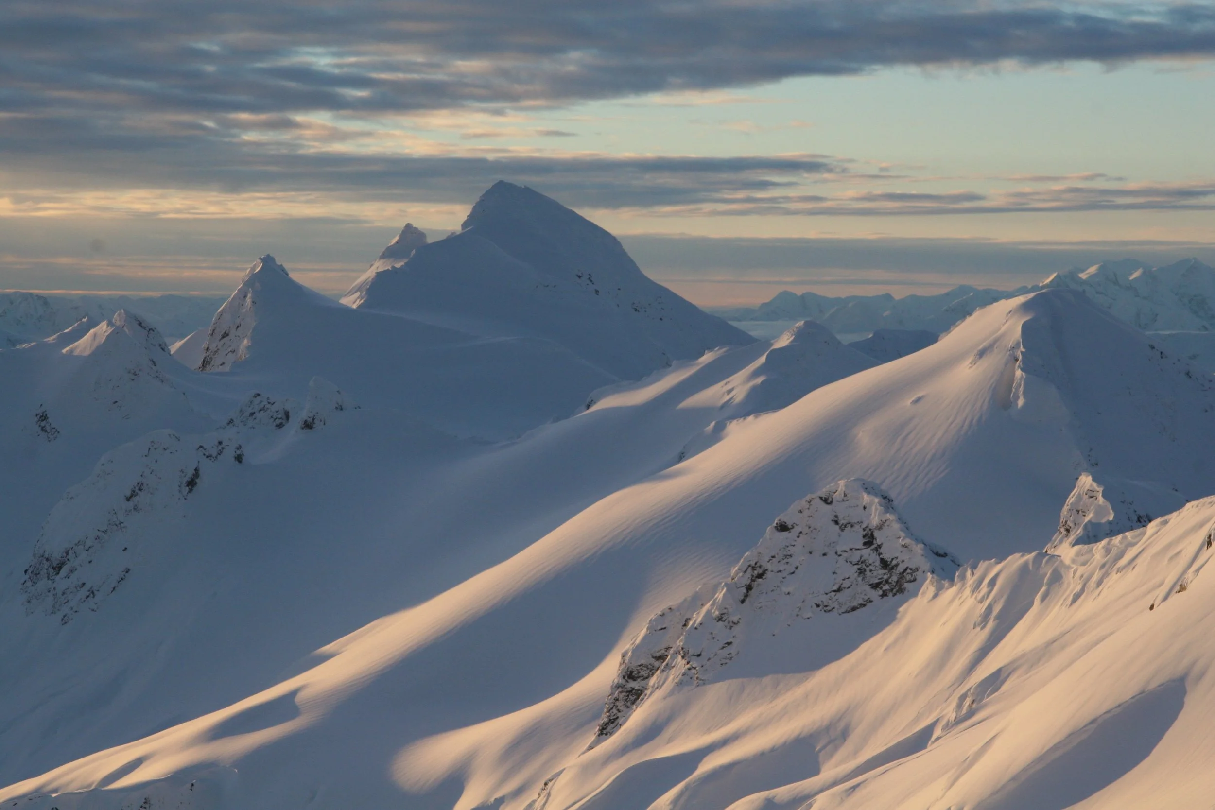 Snow-covered mountains glowing at sunset in Northern British Columbia