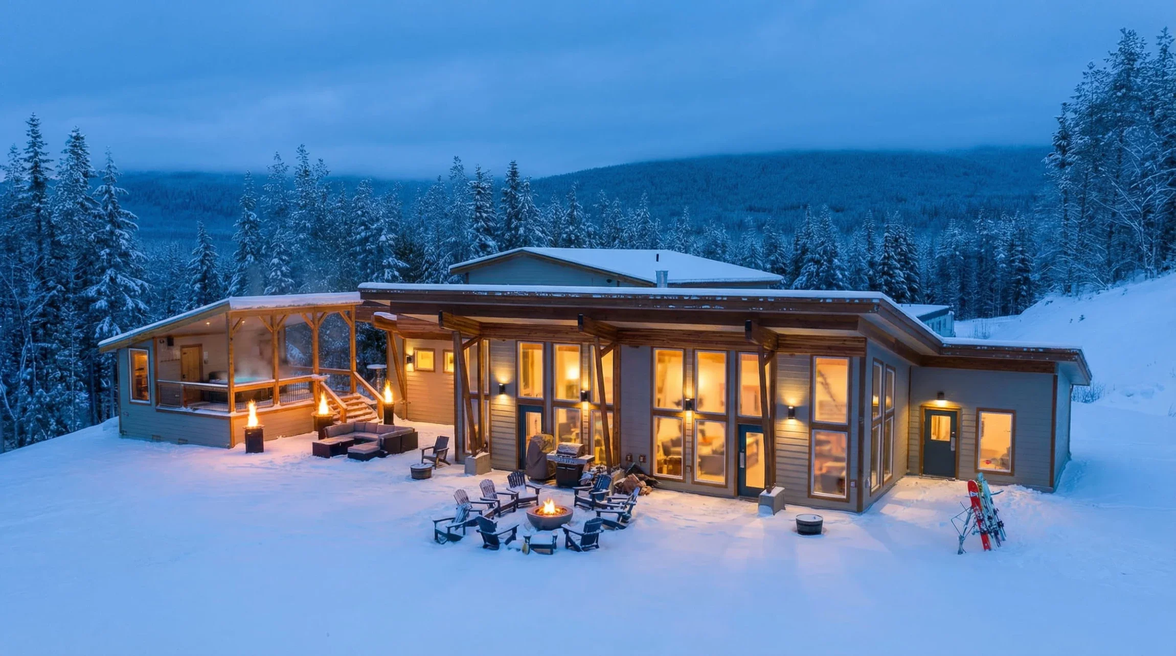 Mountain Lodge illuminated in the evening with an outdoor fire surrounded by snow