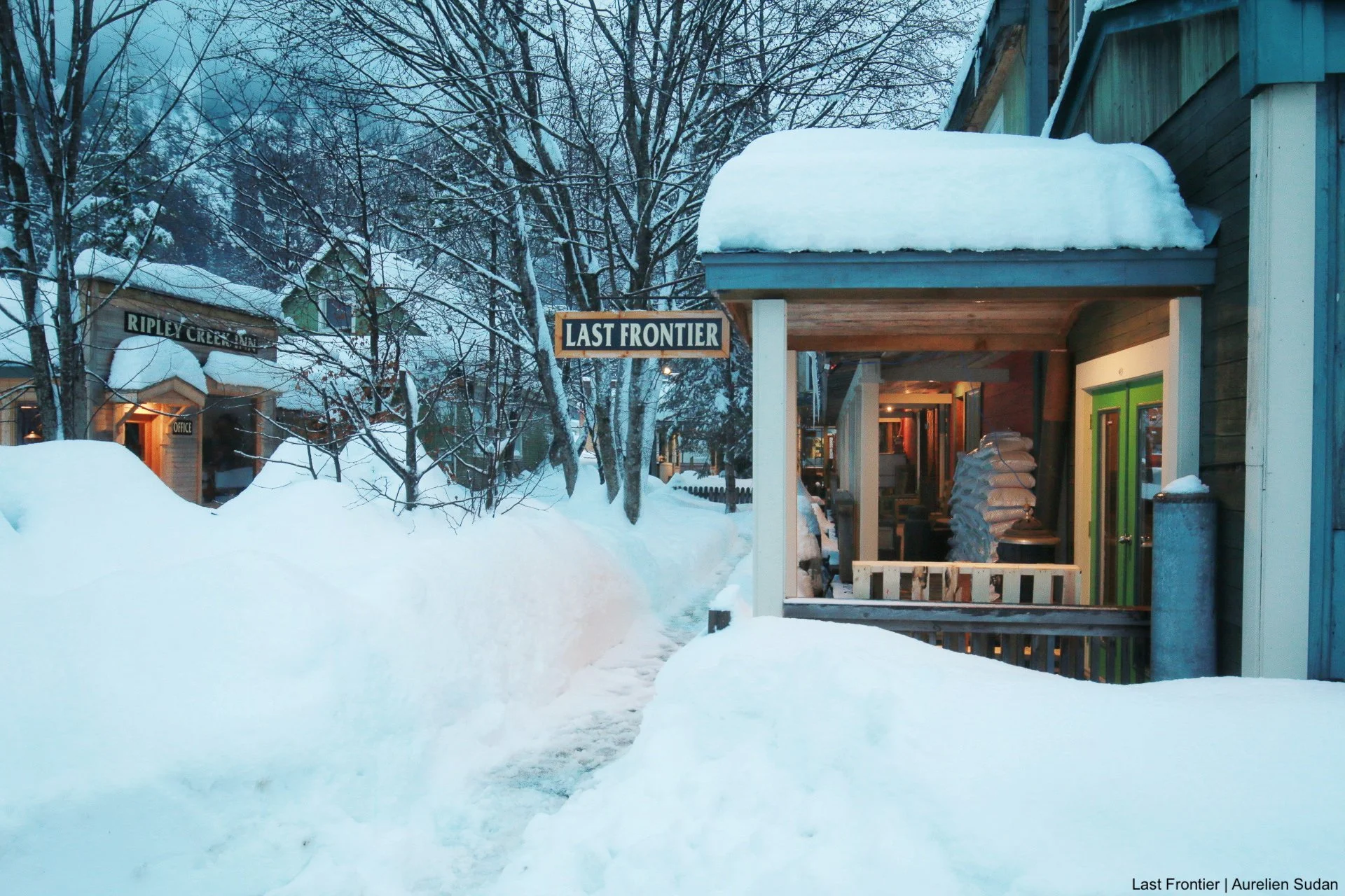Deep winter snow covering the streets of Stewart, BC, with the town's historic buildings in the background.