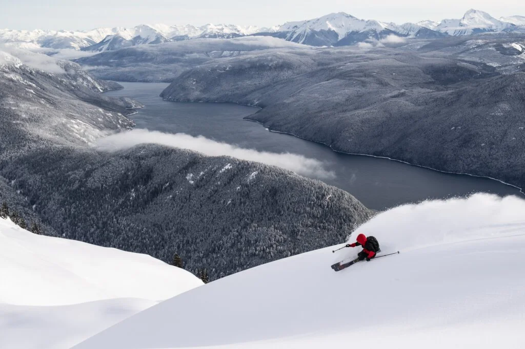 Skier making a turn on a high ridge overlooking Quesnel Lake at Silvertip.