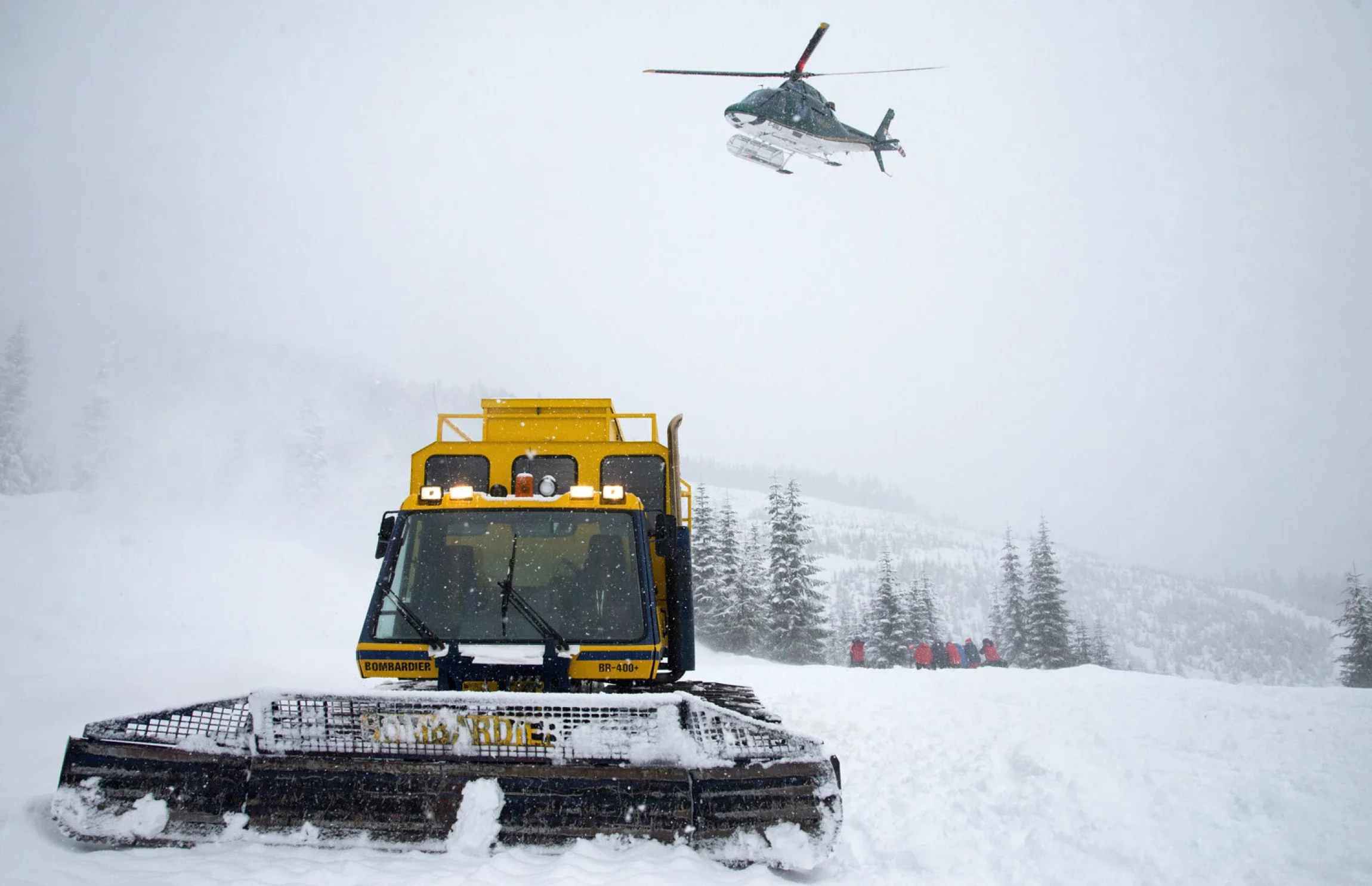 Helicopter landing beside a snowcat during a Northern Escape ski trip