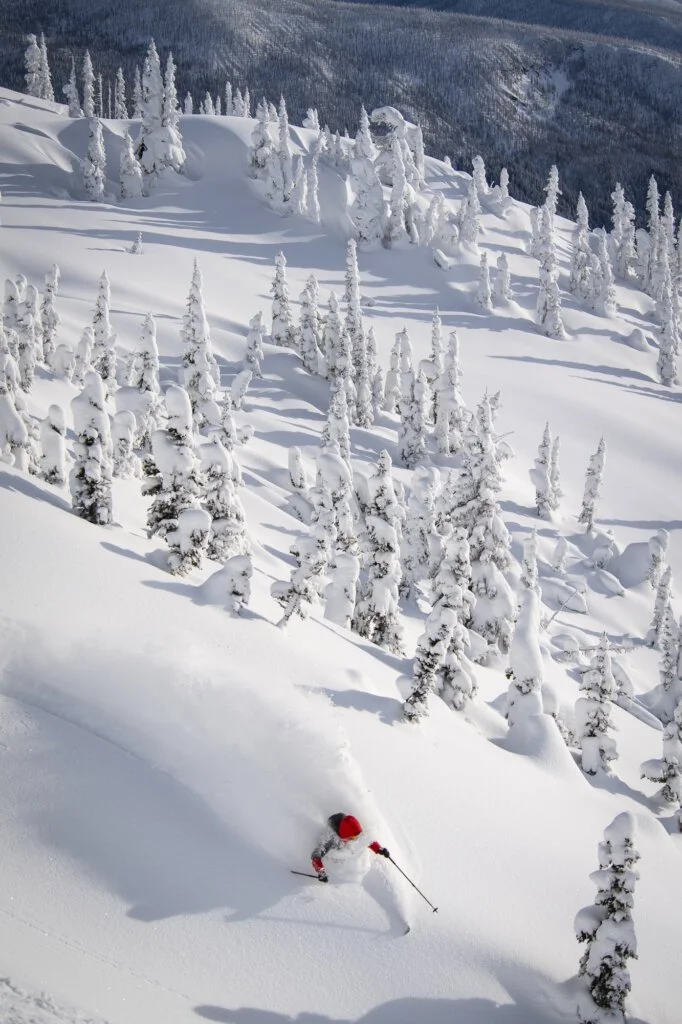 Skier slashing a turn along a ridge near treeline at Silvertip.