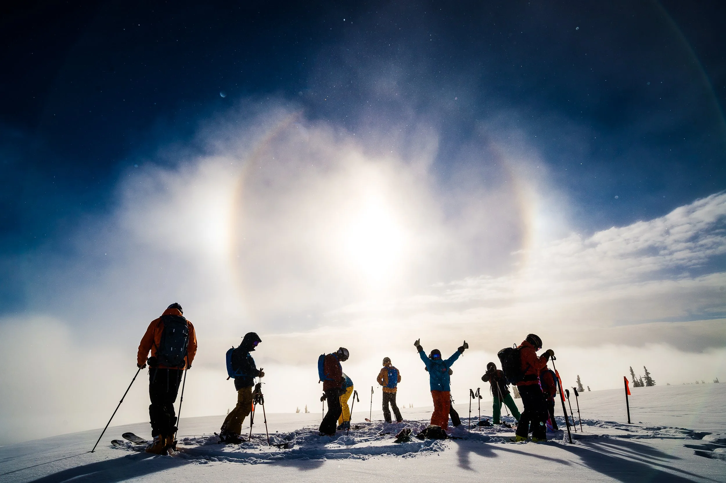 Heli-skiing group preparing to drop into fresh powder on a clear bluebird day.