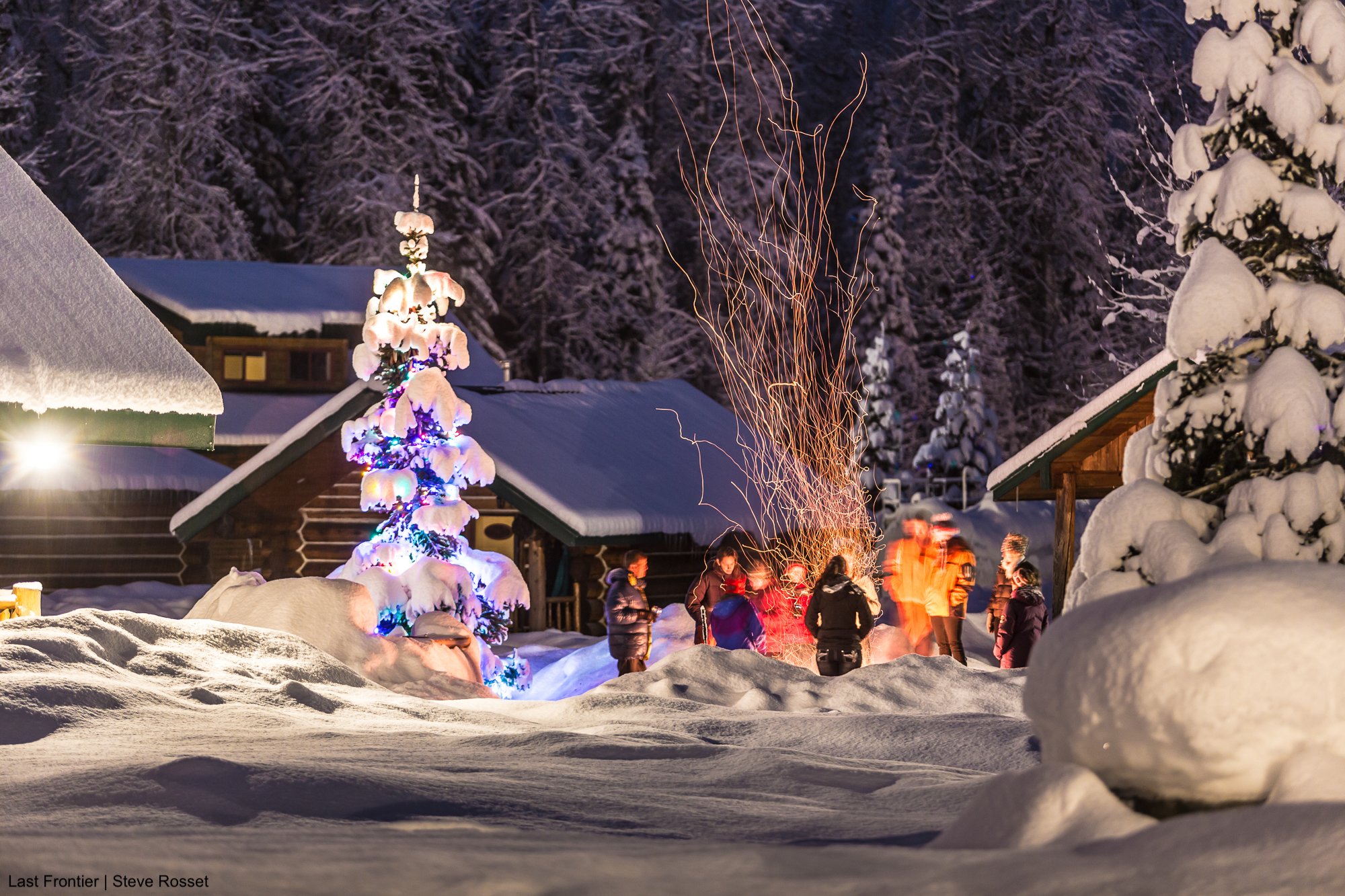 Guests gathering around the fire pit at Bell 2 Lodge after a day of heli skiing.