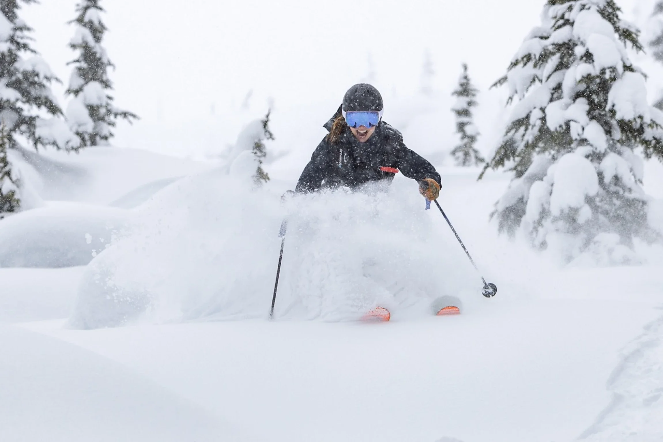 Smiling skier skiing through powder-filled glades