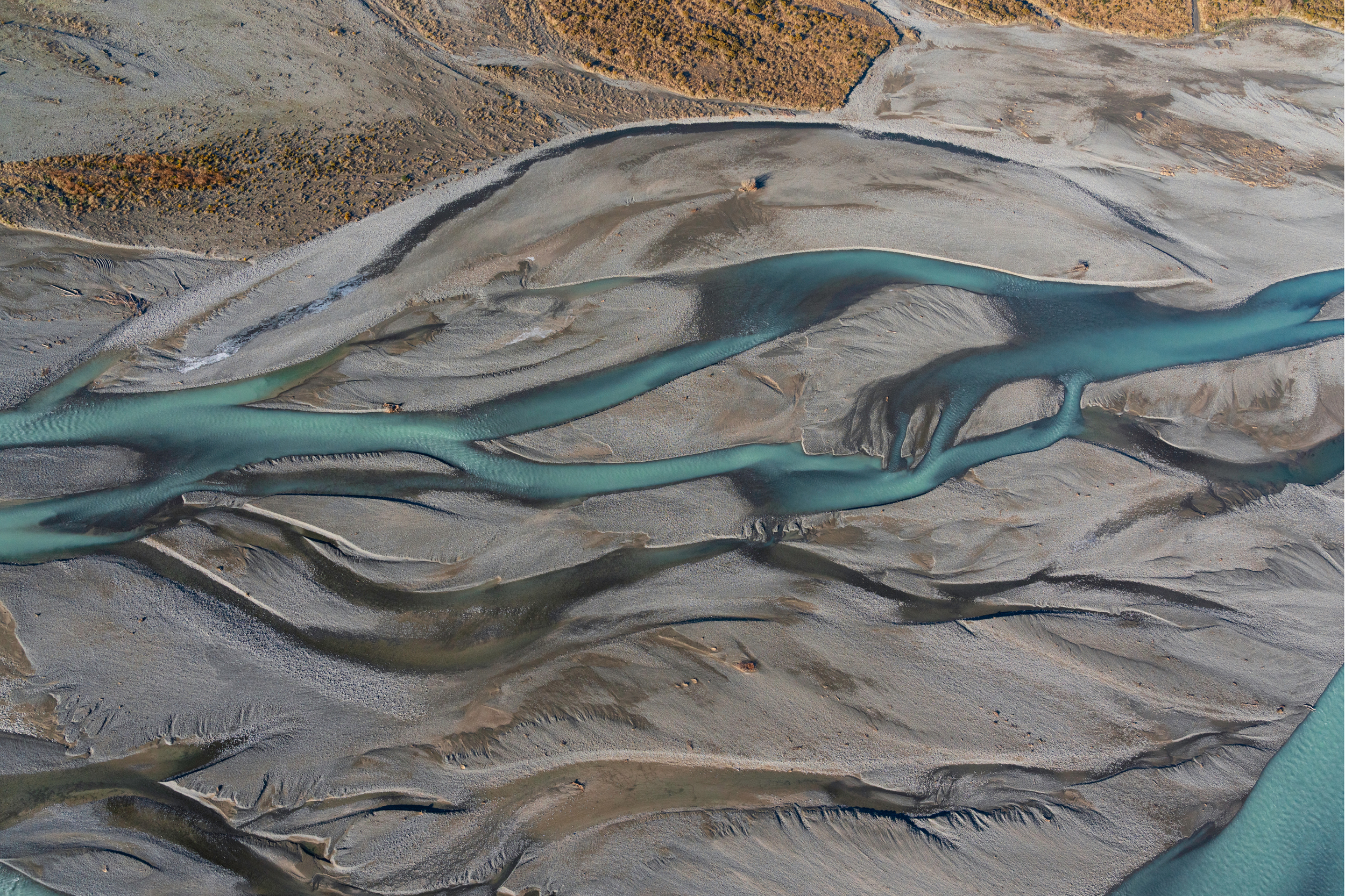Aerial view of a river with multiple channels flowing through a barren, rocky landscape.