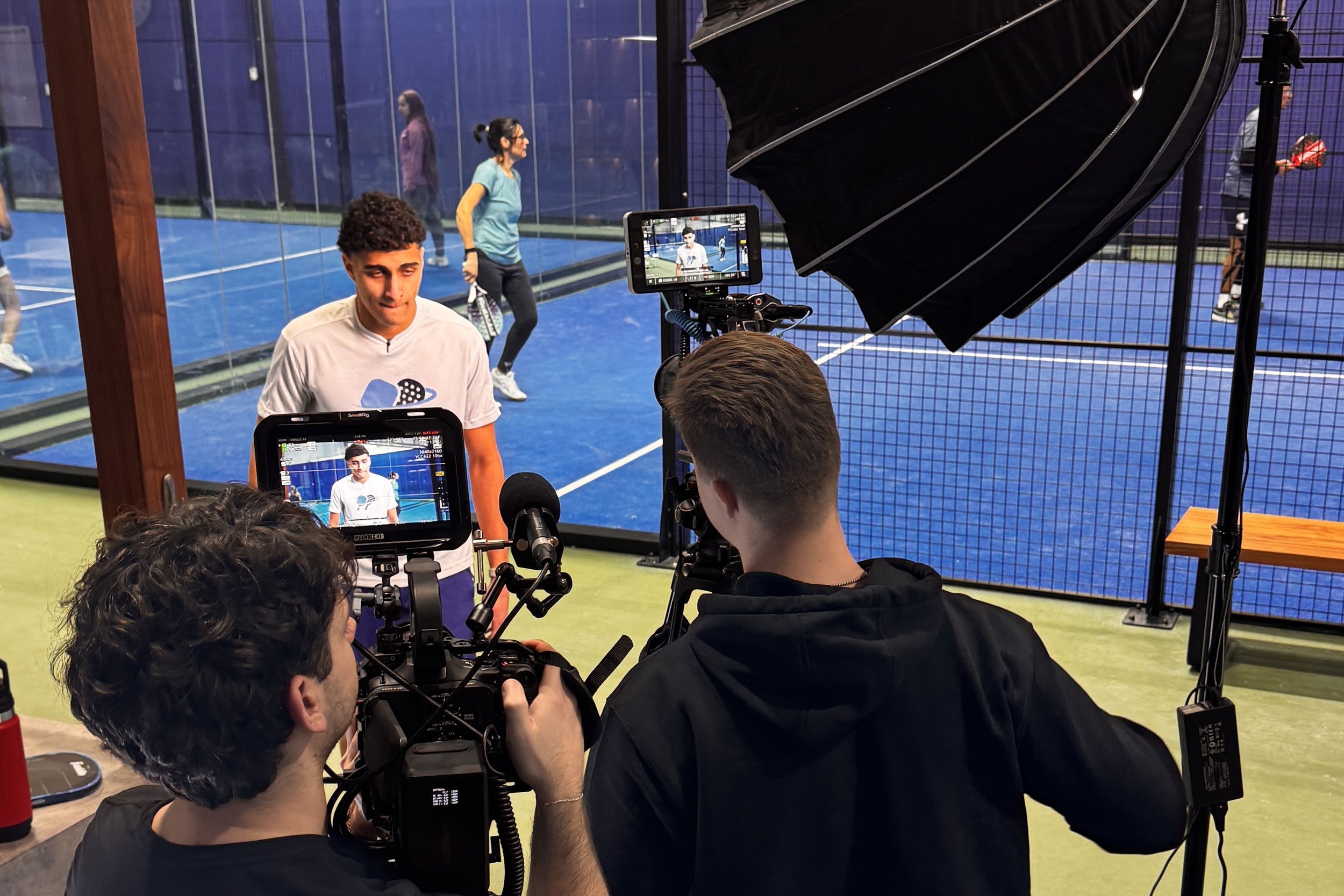Deadline Creative filming branded sports content at Blue Zone Courts with professional cameras, studio lighting, and indoor padel courts in the background.