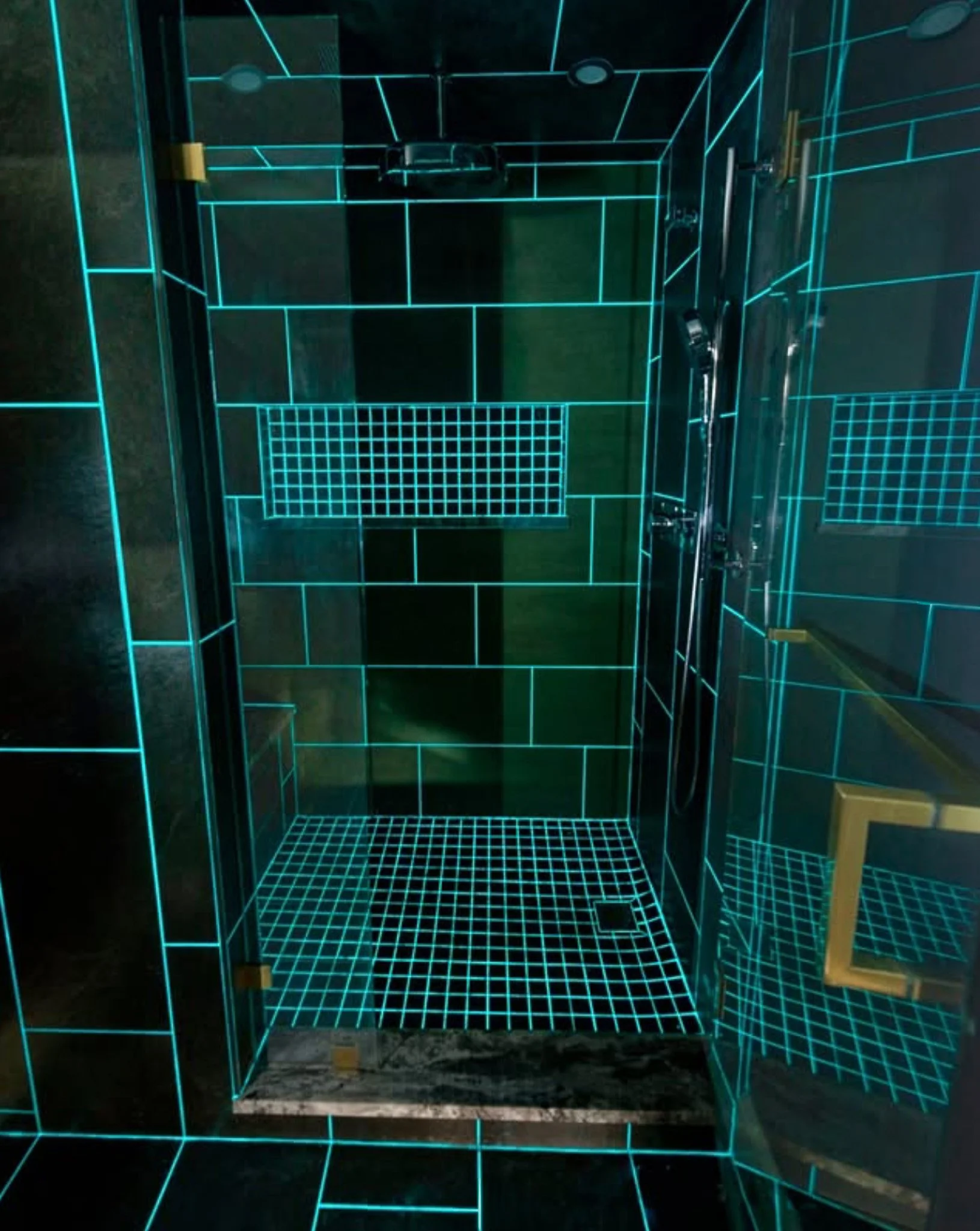 Inside a futuristic shower enclosure with black walls and floor, illuminated by blue neon grid lines outlining the structure and features, including multiple adjustable showerheads.