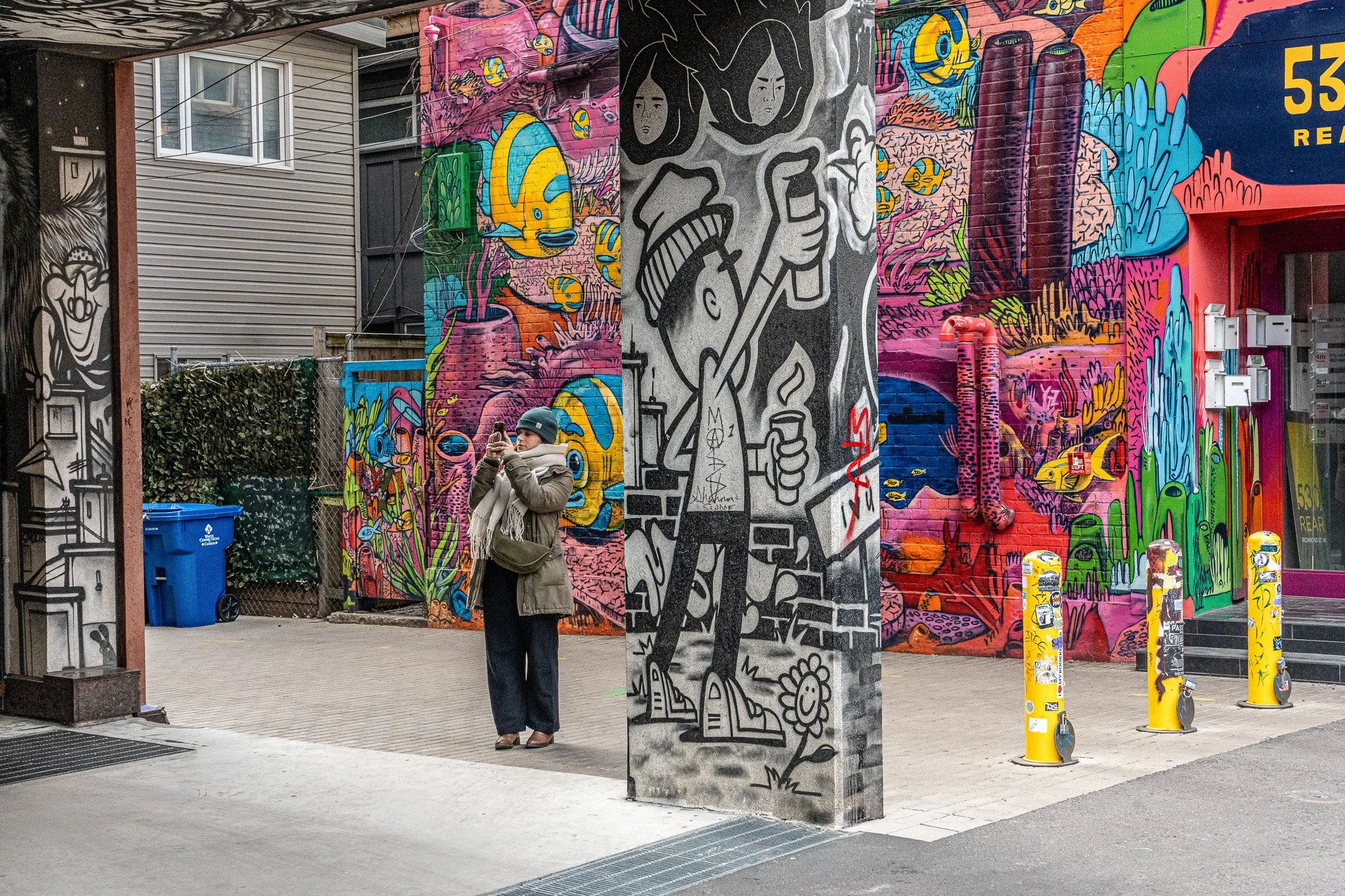 Street scene on Queen Street West, Toronto, with a passerby framed between bold mural walls and graphic urban artwork.