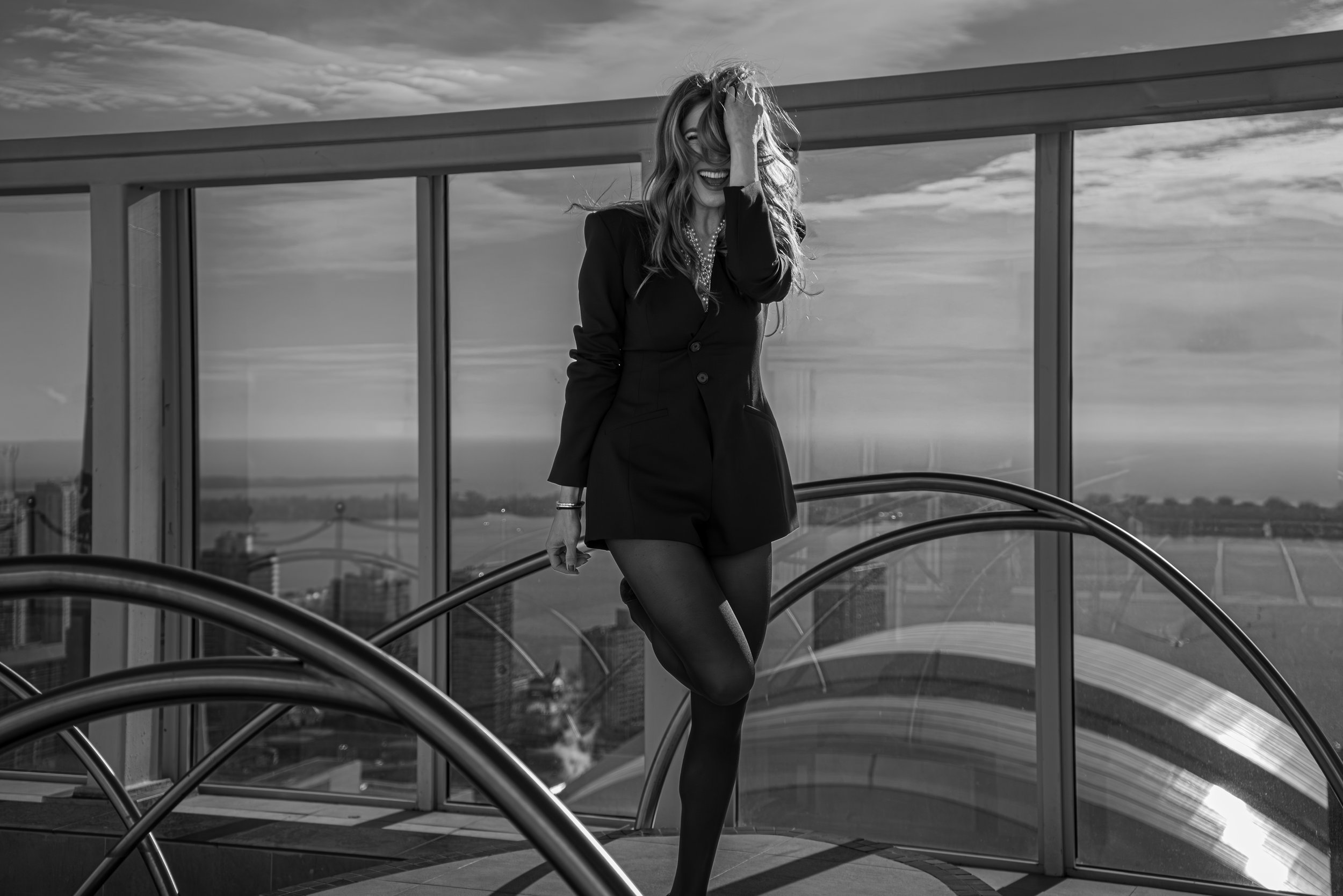 Black and white editorial portrait of a woman standing on a modern rooftop, structured tailoring and architectural lines creating a strong silhouette.
