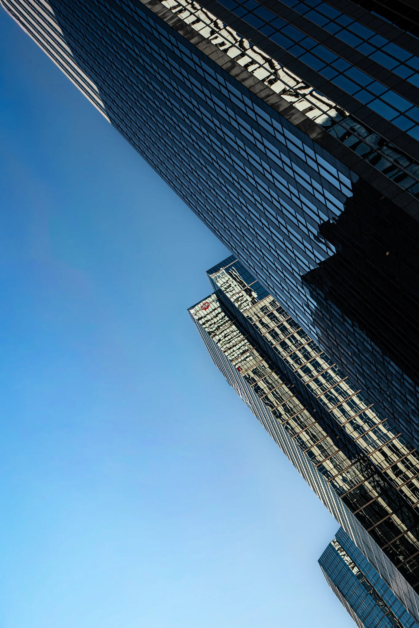 ow angle composition of intersecting skyscrapers, emphasizing transparency, structure, and the movement of sky mirrored in glass façades.