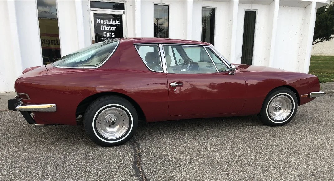 Side profile of Dark Red 1983 Avanti II showing chrome factory mirrors.