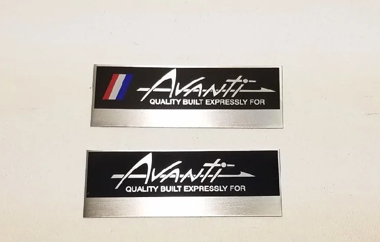 NOS Studebaker Avanti dash plaques showing both available styles: with stripes and without stripes.