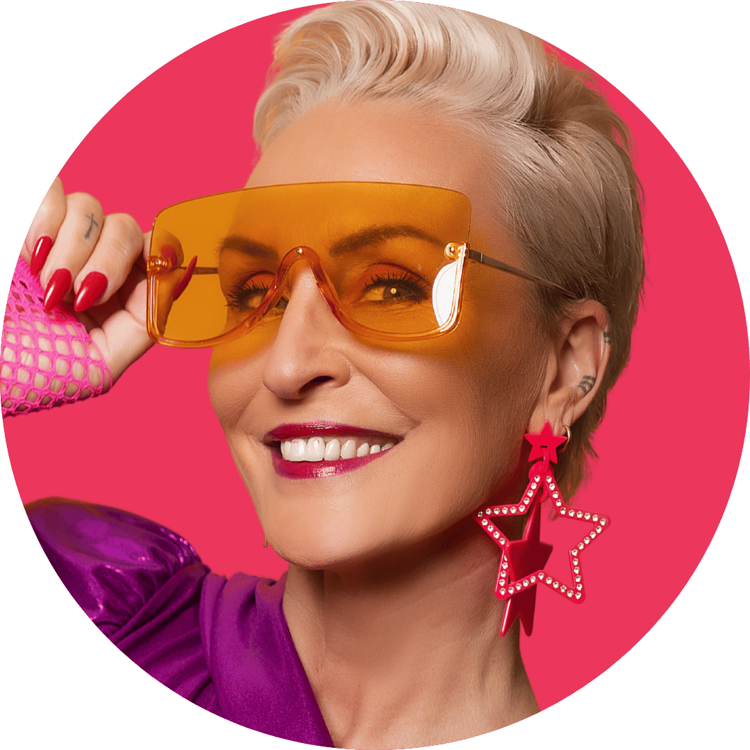 Nadine Miree mit kurzem blondem Haar trägt große orange Sonnenbrille, pinkes Netz-Top und große pinke Stern-Ohrringe vor pinkem Hintergrund.
