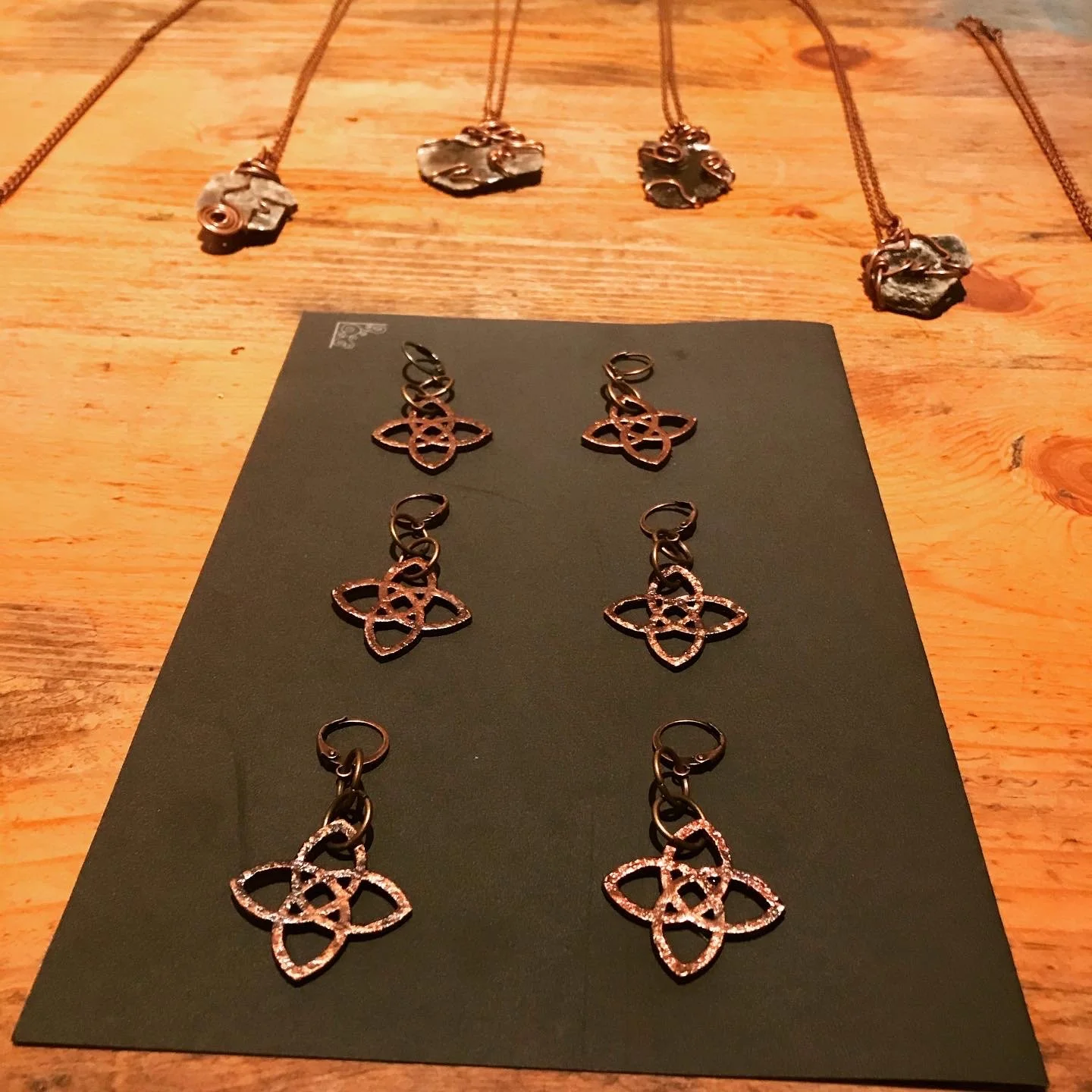 Collection of necklaces and earrings displayed on a wooden surface and black display sheet.