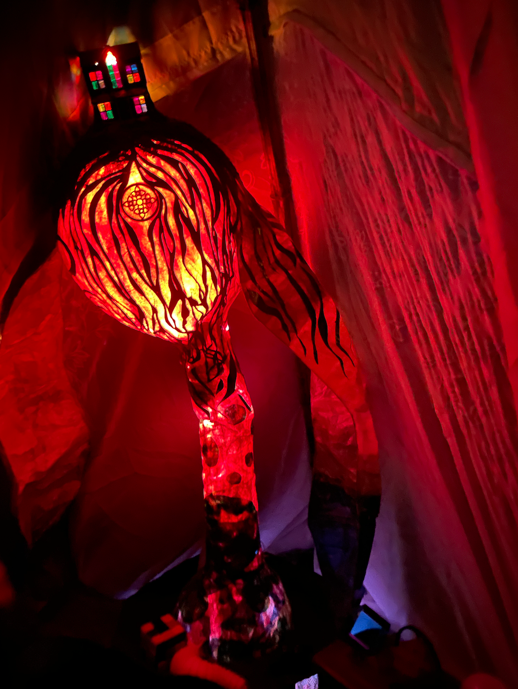 A vibrant, glowing lamp with a zebra print pattern, emitting a bright red and orange light in a cozy, dimly lit room.