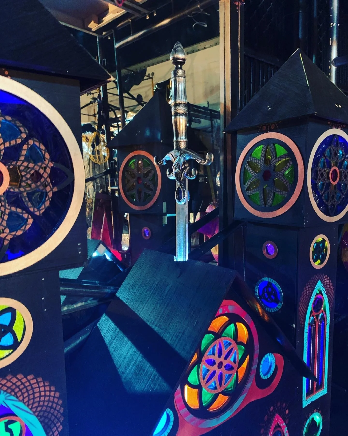 Colorful illuminated stained glass-inspired art and a decorative sword.