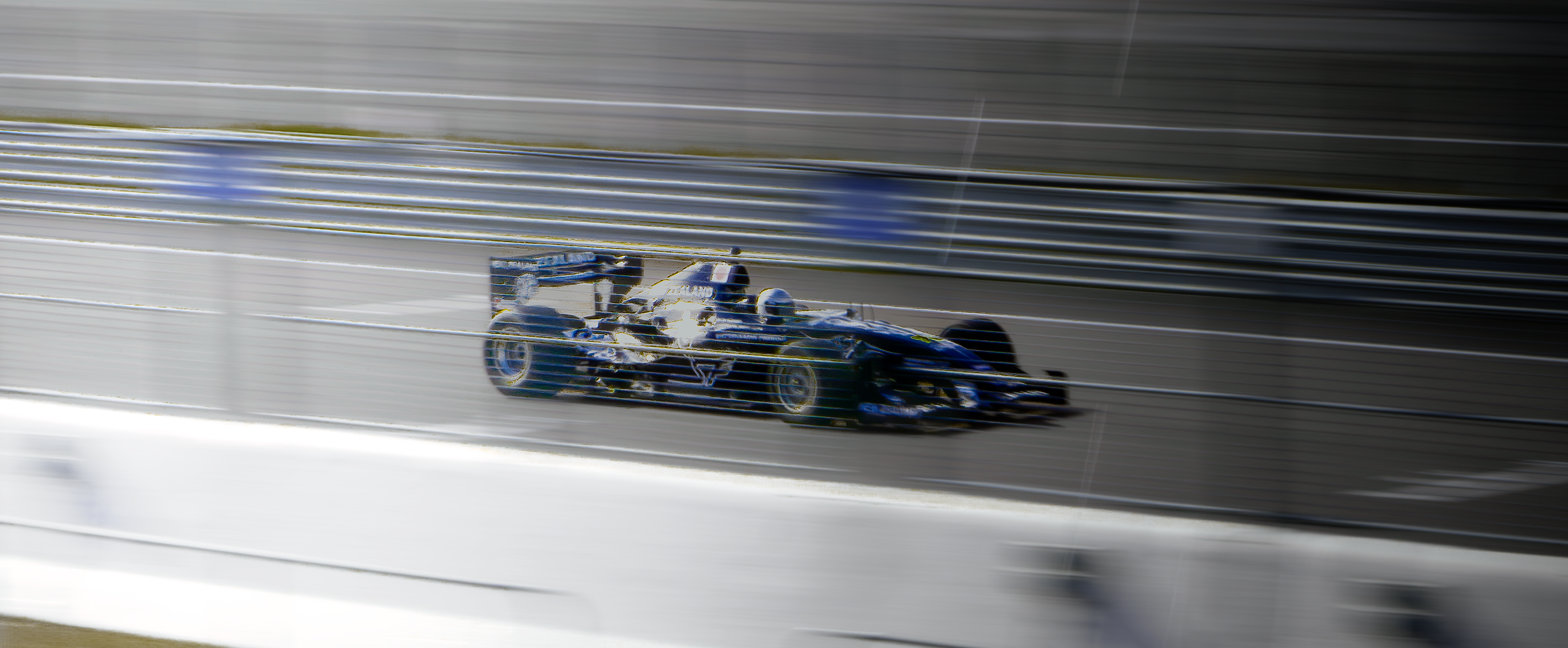 Voiture de course de Formule 1 roulant à grande vitesse sur une piste de course, vue floue en raison de la vitesse.