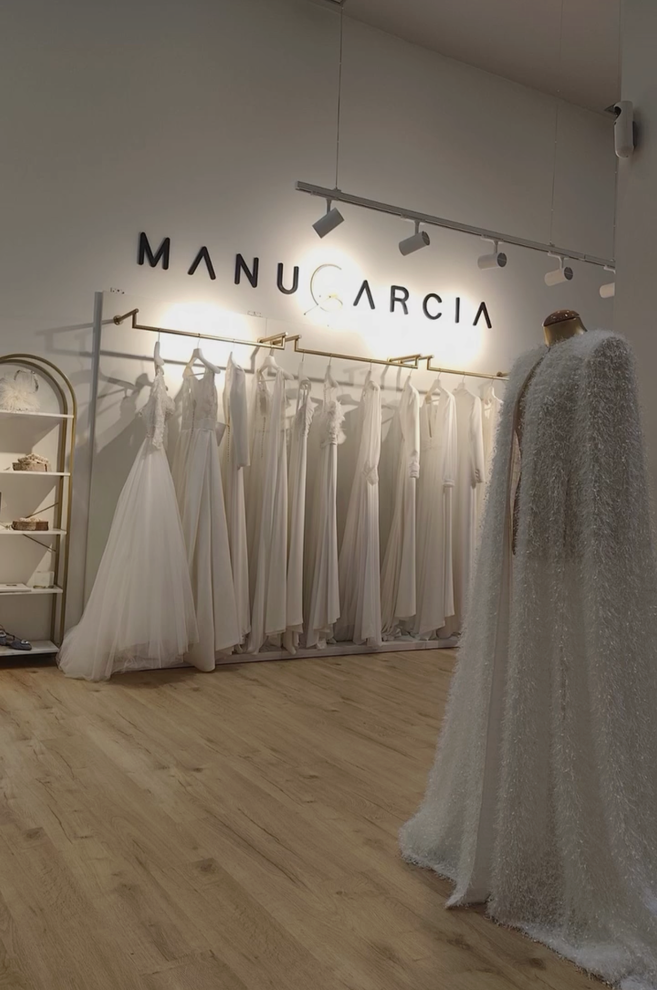 Vestidos de boda blancos en una tienda llamada Manucaria, con una exhibición de vestidos y una maniquí con vestido de novia
