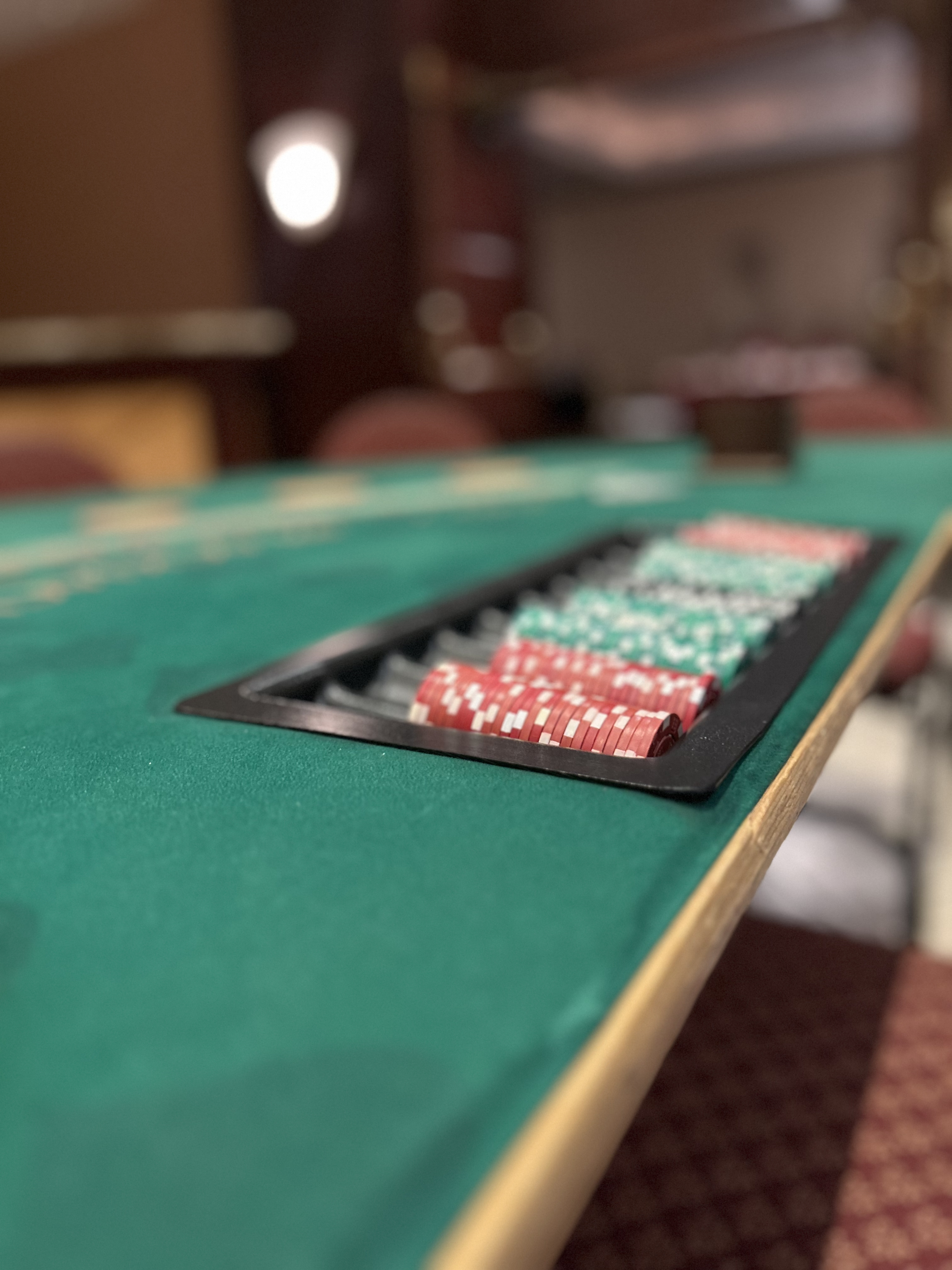Close-up of a roulette table with red and green chips on the betting area in a casino. The background is blurred.