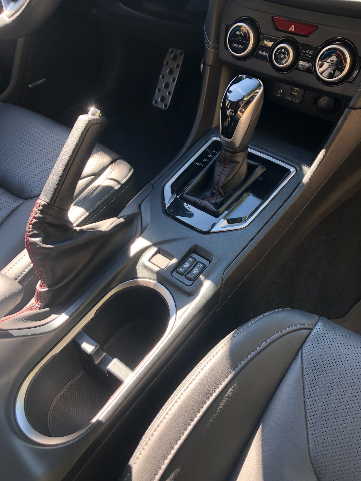 Close-up of freshly detailed vehicle interior featuring gear shift, cup holders, and spotless leather seating.