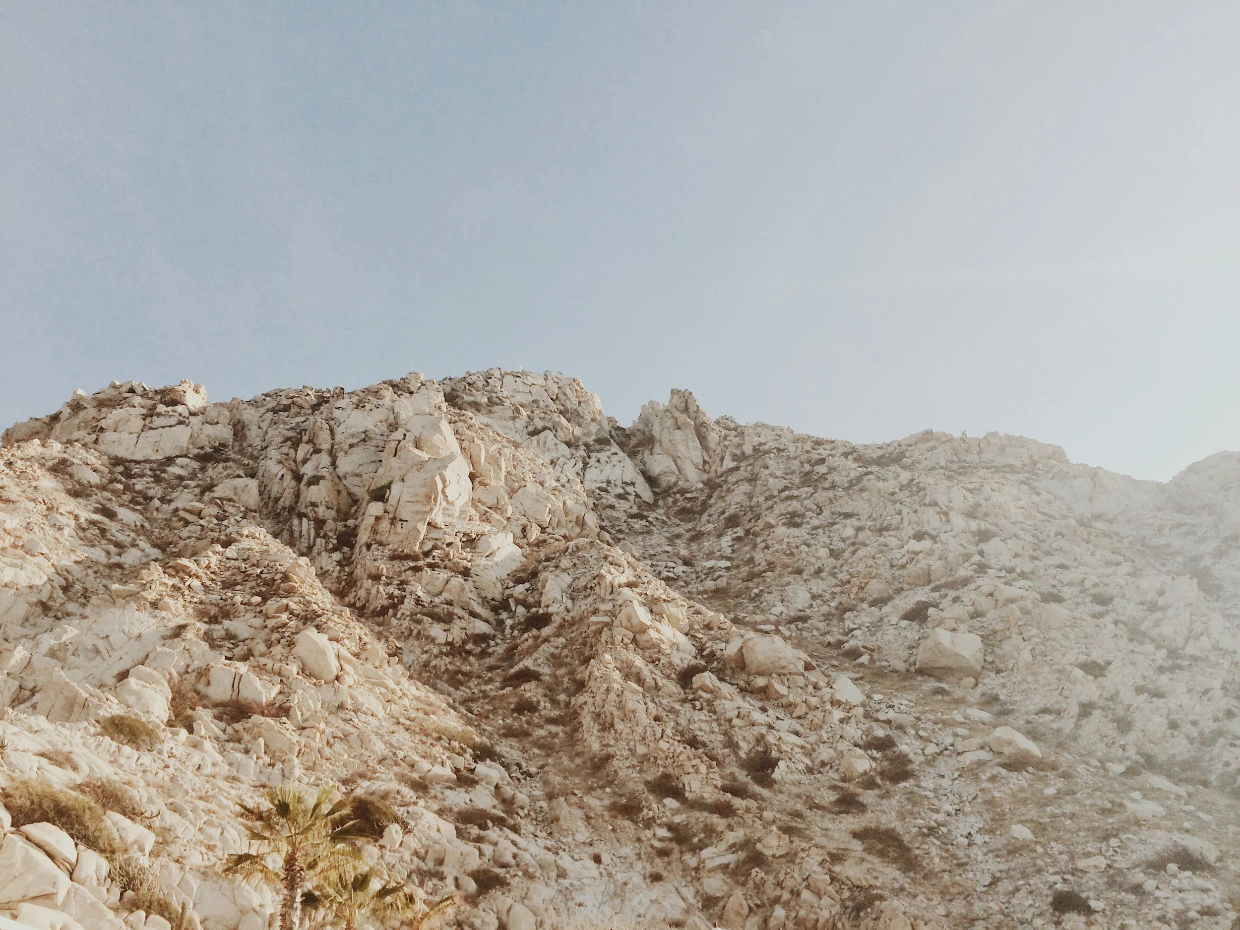 A rocky mountain landscape with a clear blue sky overhead.
