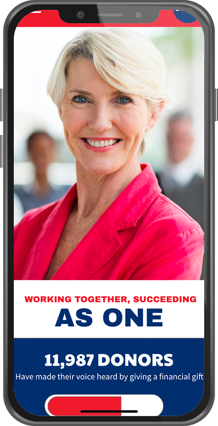 A woman with short blonde hair, wearing a pink blazer, smiling at the camera in a professional setting, with blurred people in the background.