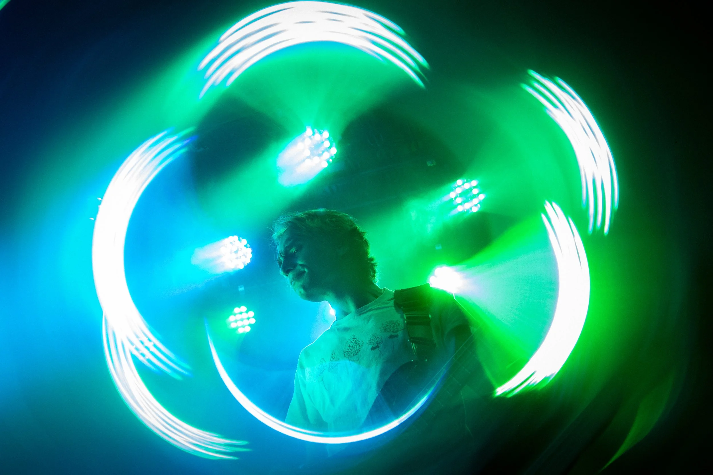Person walking through a circular tunnel of green and white LED lights at night.
