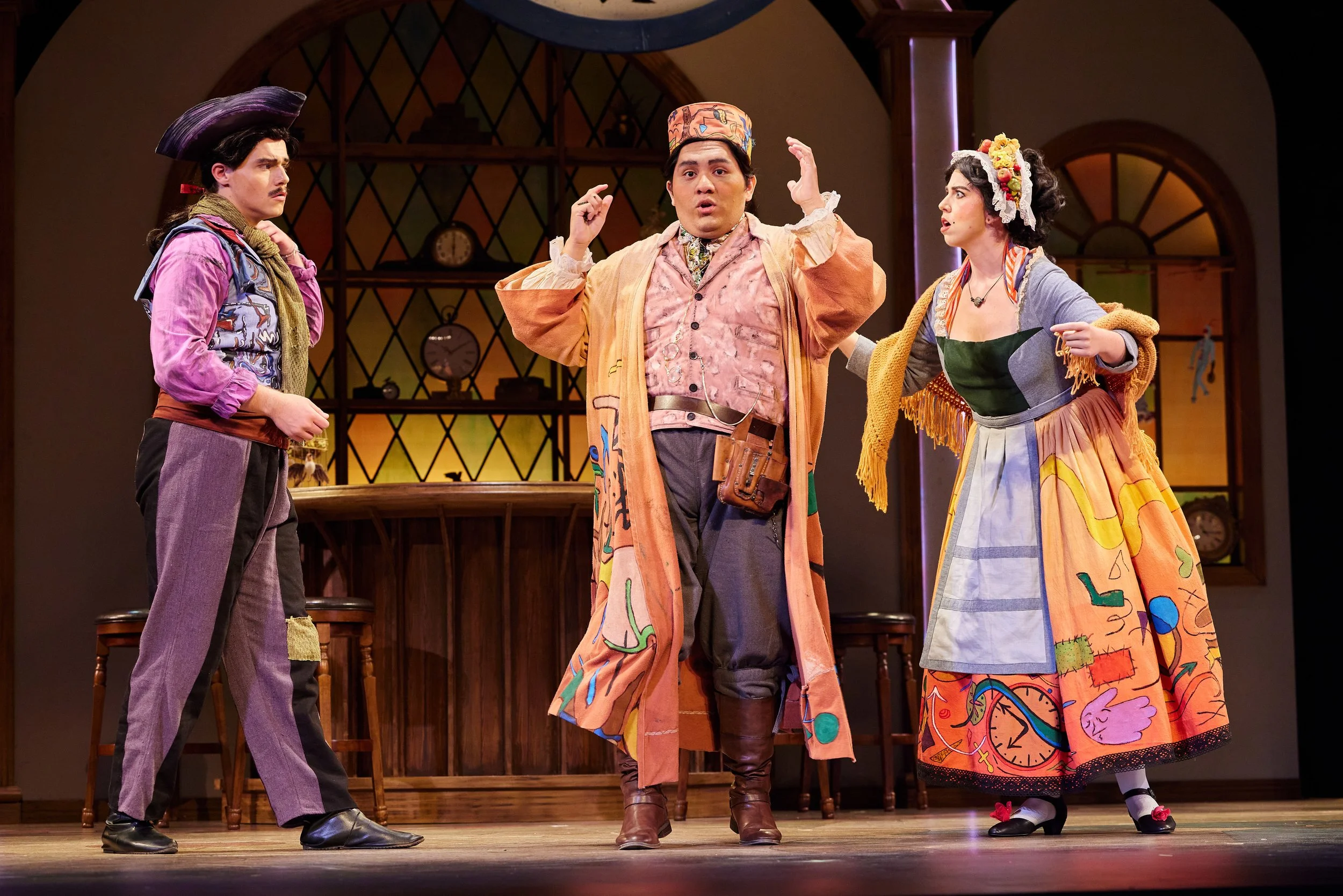 Three actors on stage performing in a play, dressed in colorful, vintage costumes, with a bar setting in the background.