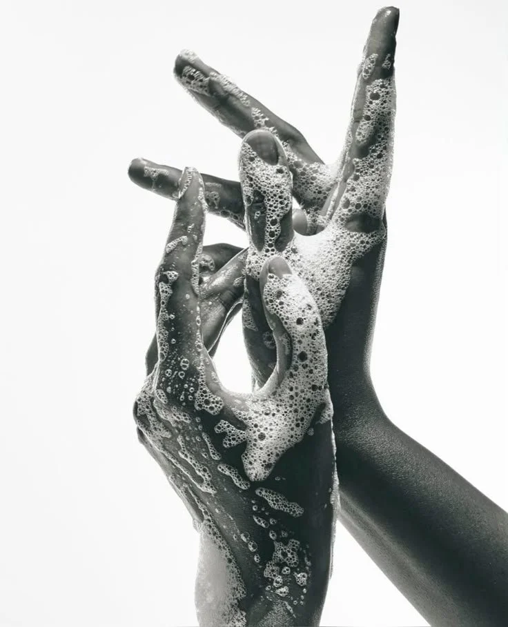 Two hands with soapy bubbles making a graceful gesture against a plain white background.